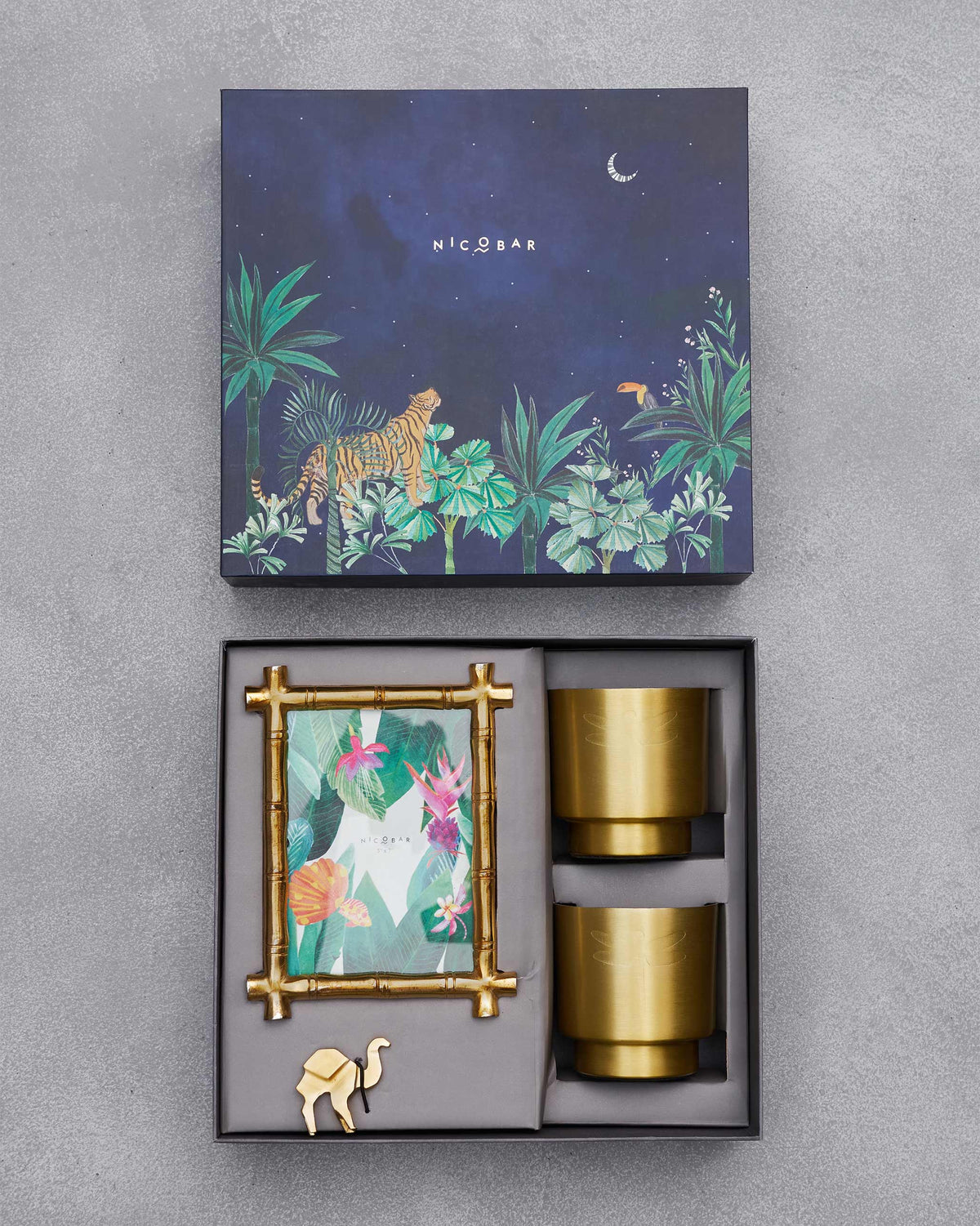 Open gilded desk gift box holding a frame, two brass planters, and a camel.