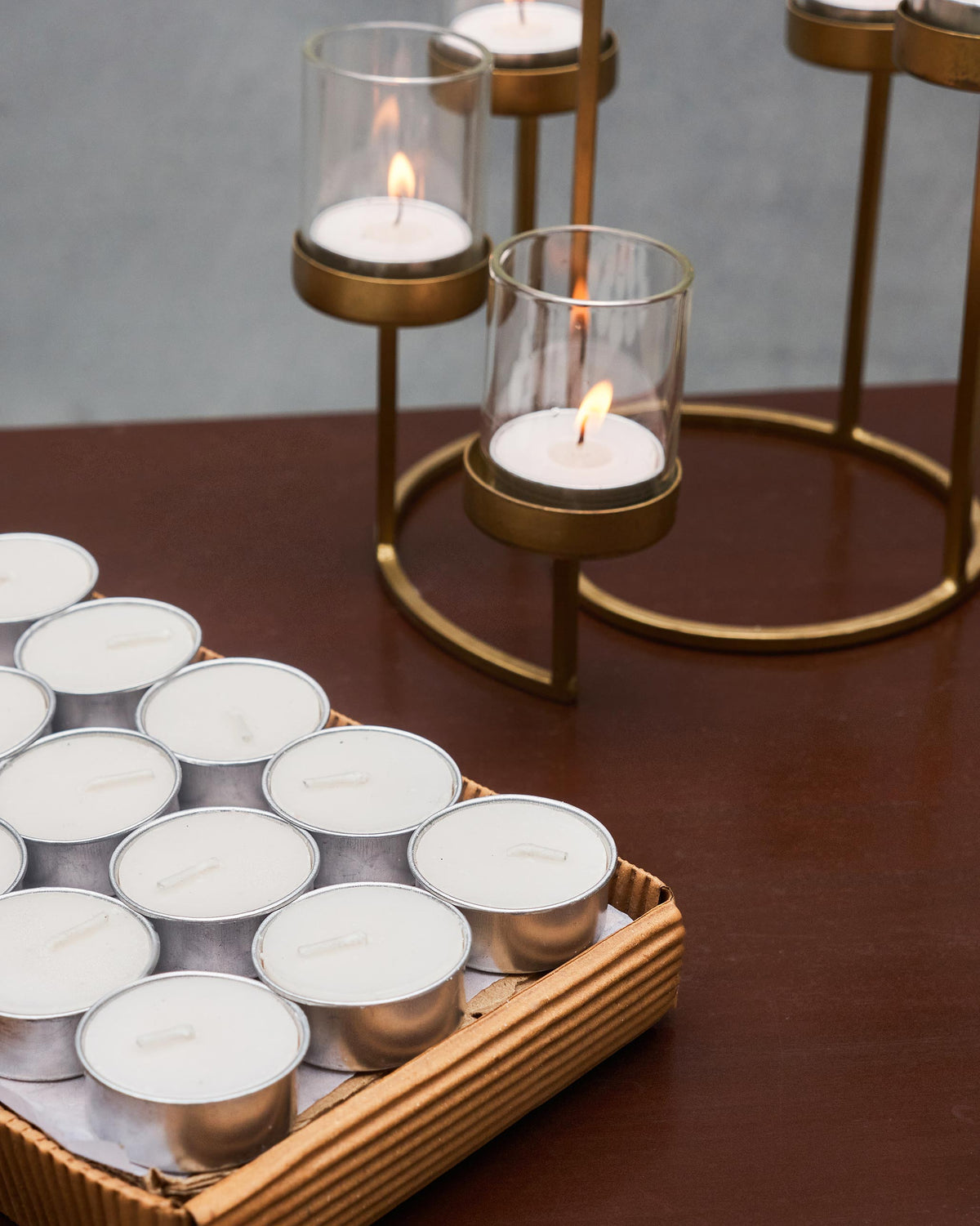 Open tray of Madurai tealights in front of a brass candle holder.