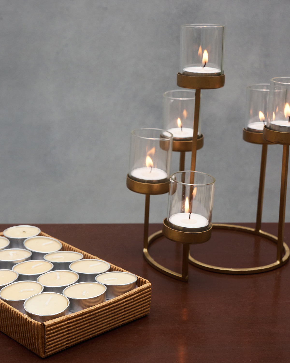 Lit Nerola tealights glowing in glass cups on a brass tiered holder.