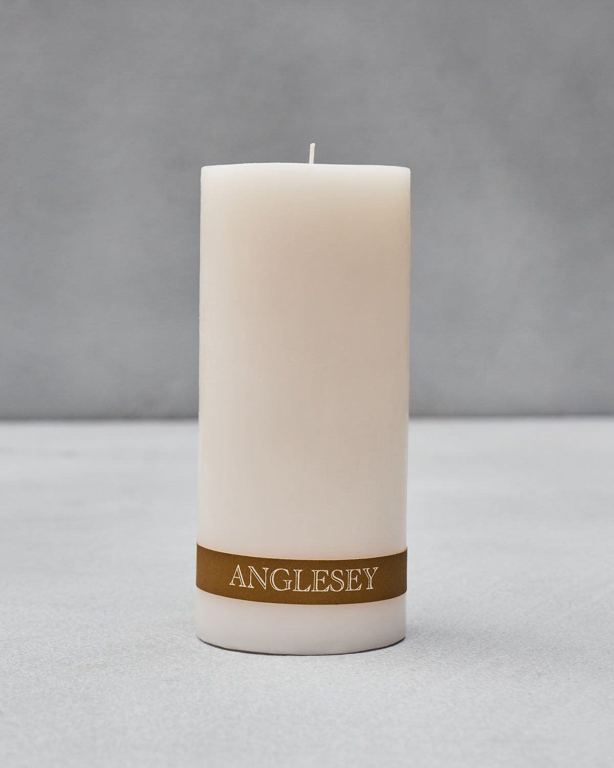 Unlit Anglesey Pillar Candle with its gold ANGLESEY label band.
