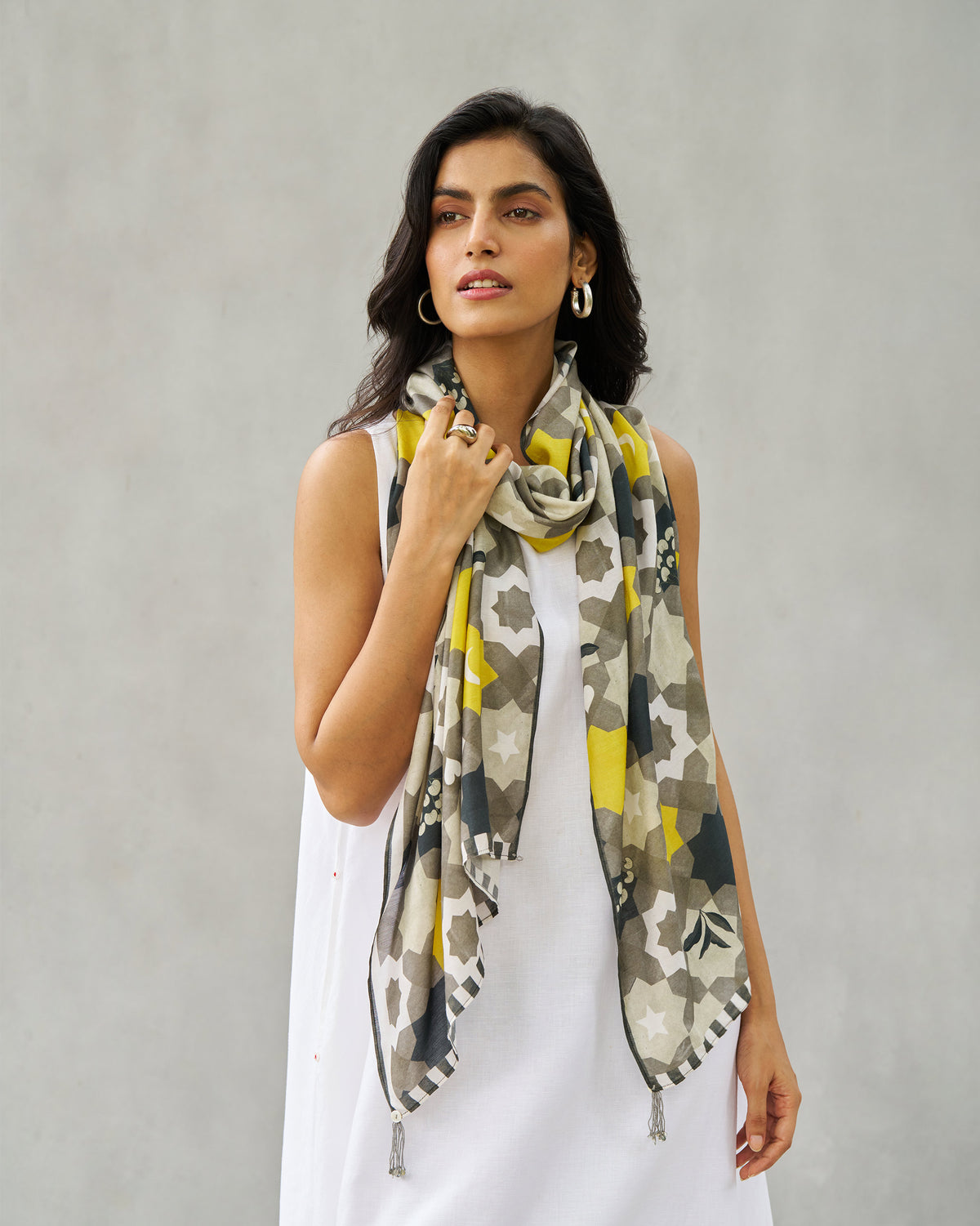 Person wearing the Celeste scarf in a geometric star tile print in grey and yellow.