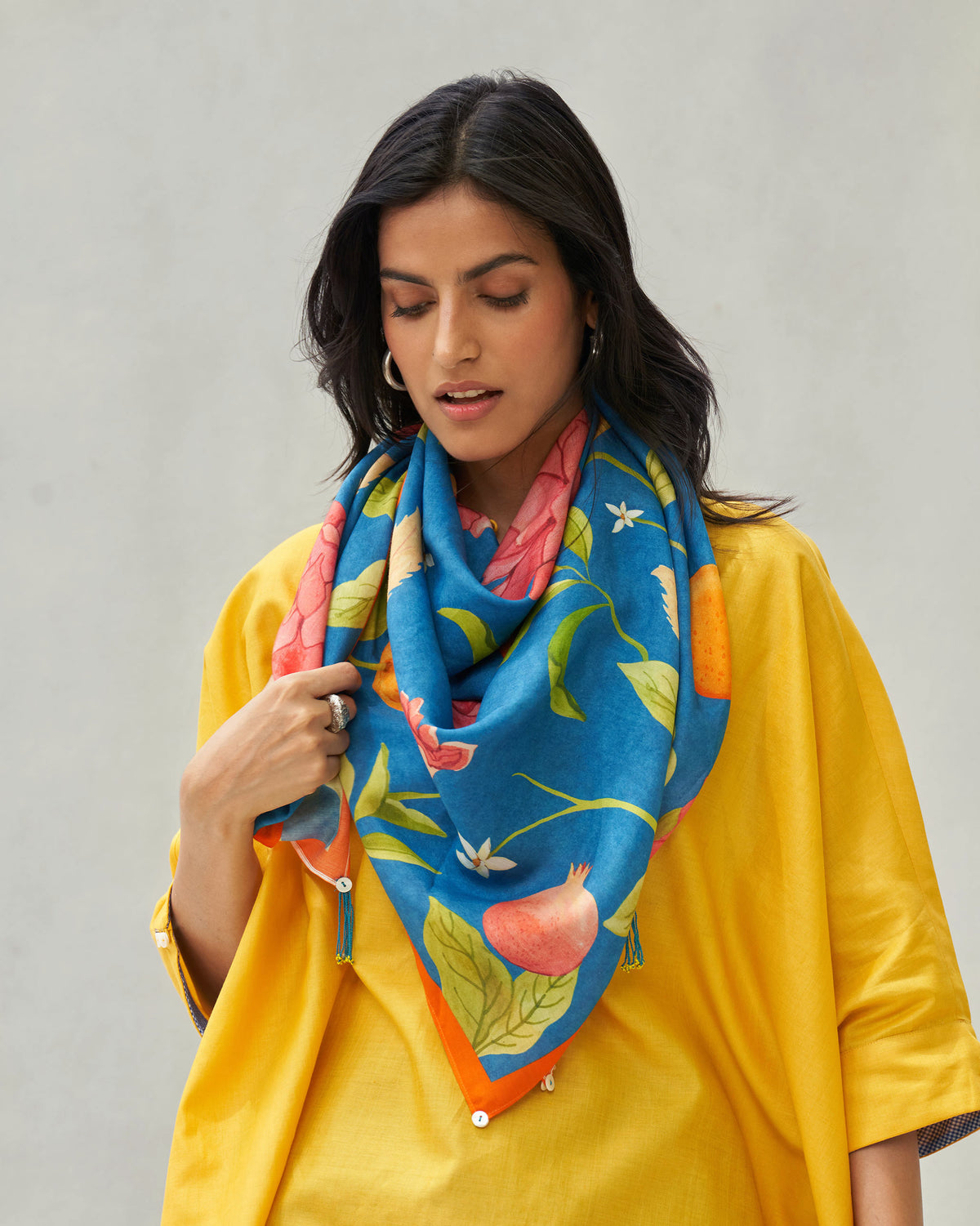 Person wearing a Midnight Garden scarf with pomegranates and pink flowers.