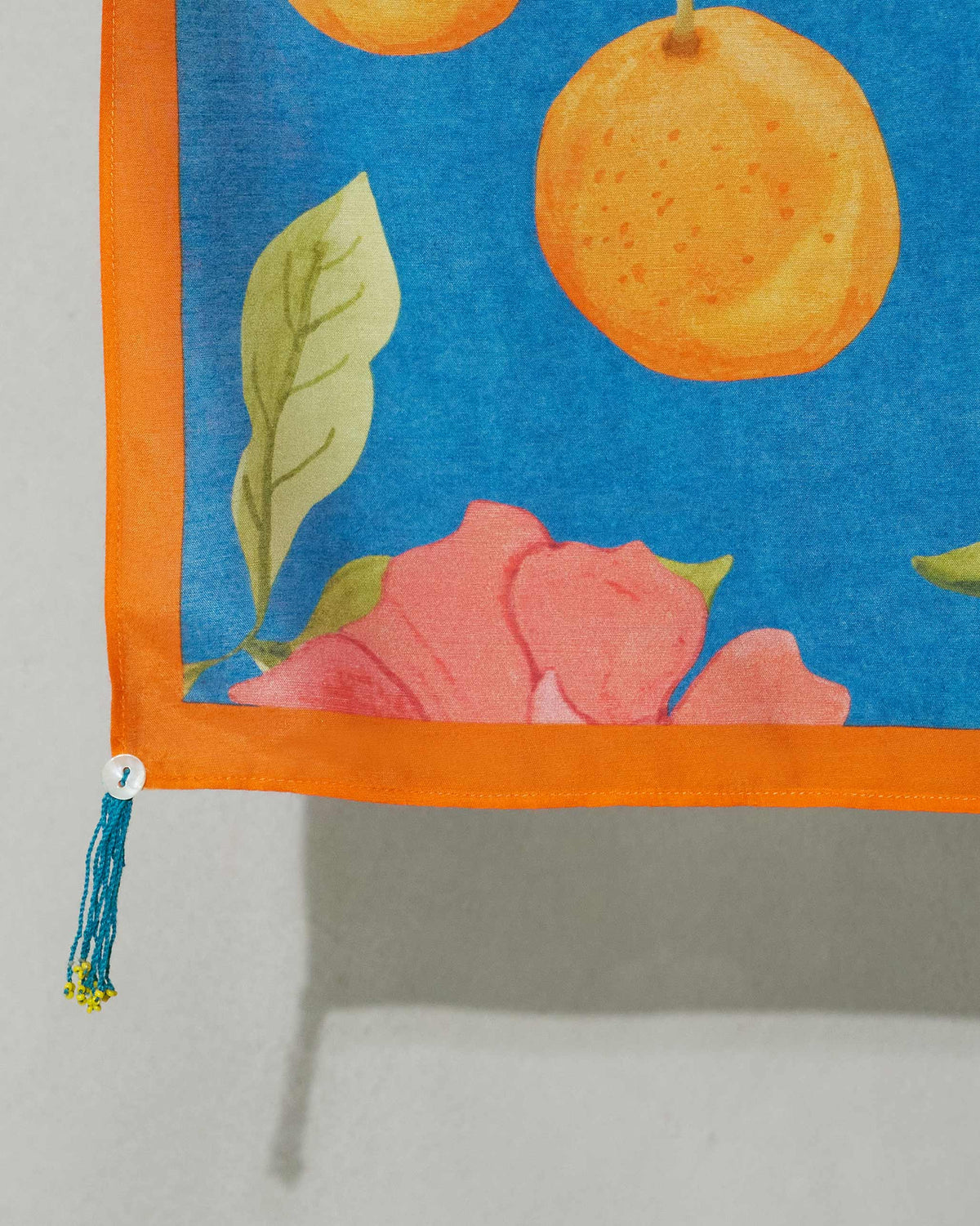 Close-up of a Midnight Garden scarf corner showing an orange fruit and a pink flower.
