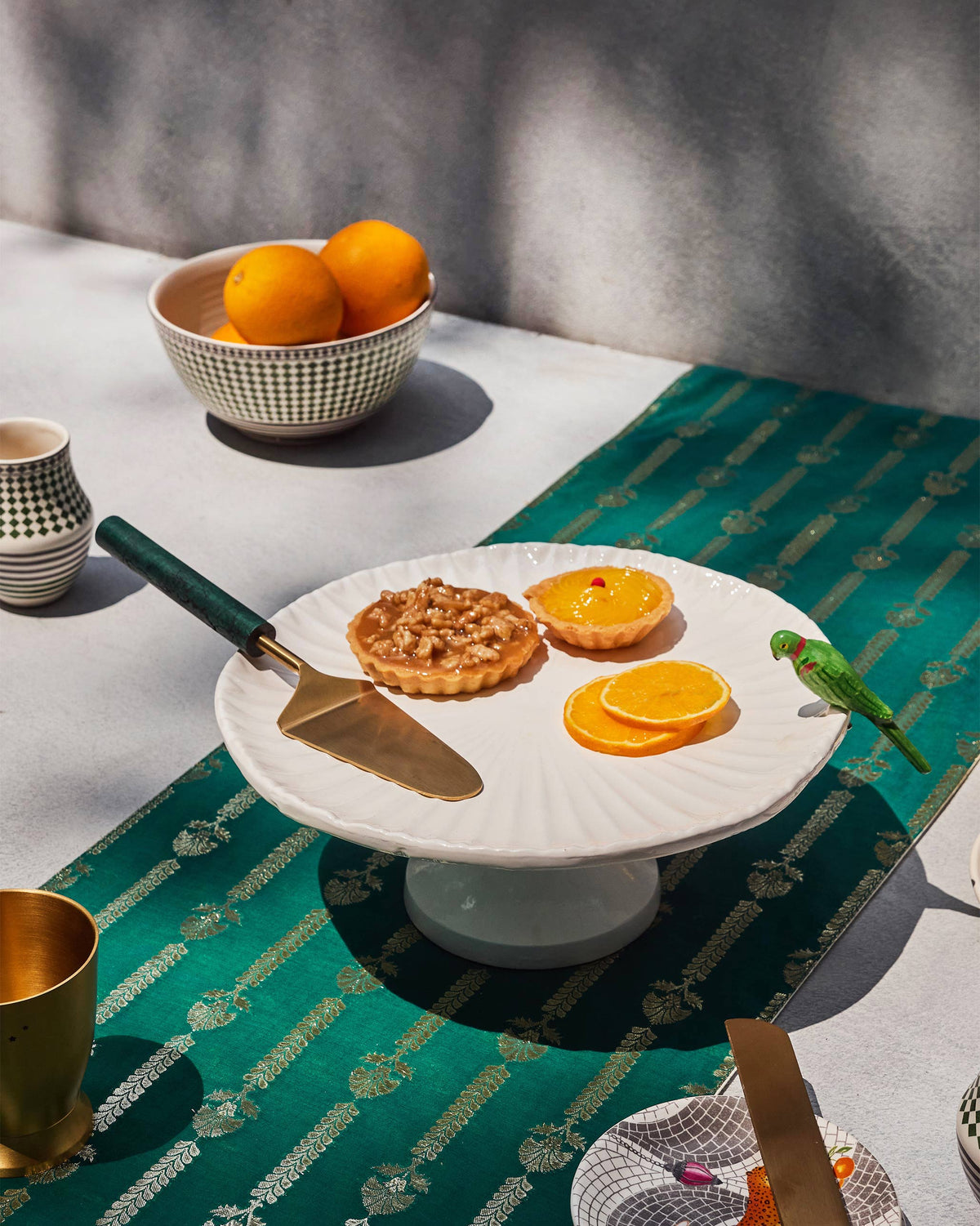 Dune Stripes Table Runner in green, styled under a cake stand with tarts.