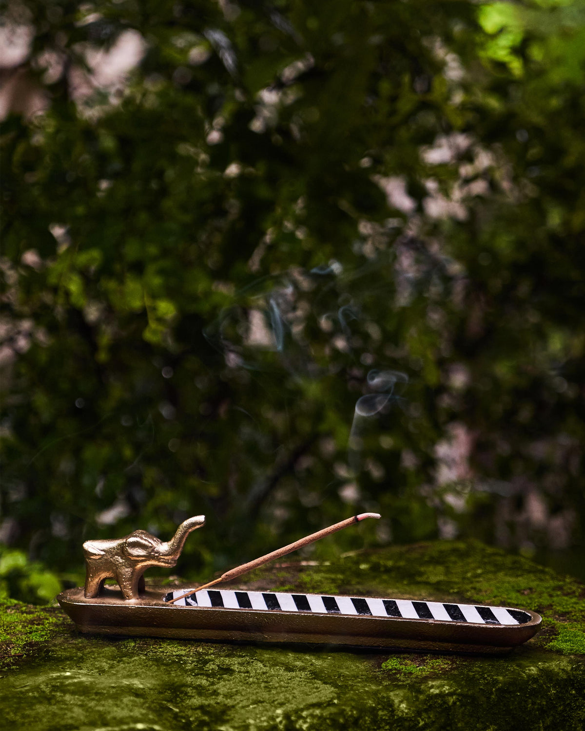 Brass Haathi incense holder with a striped tray and lit incense.