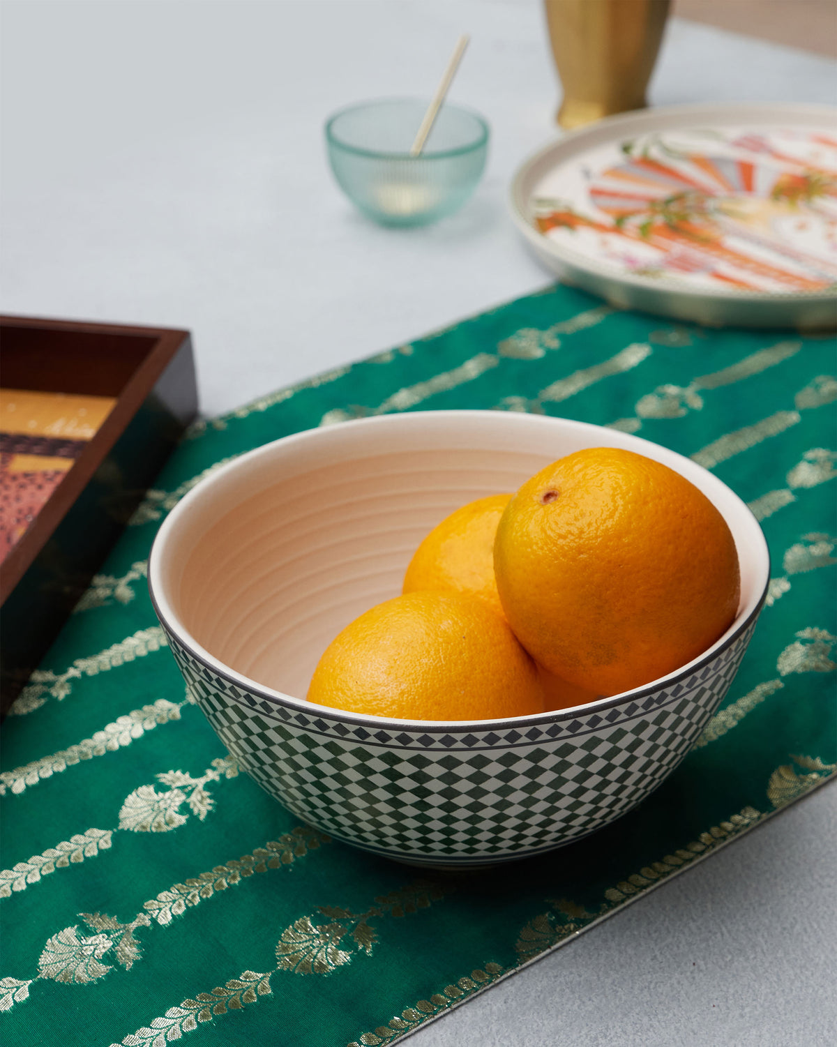Zellij Serving Bowl filled with oranges, set on a green runner.