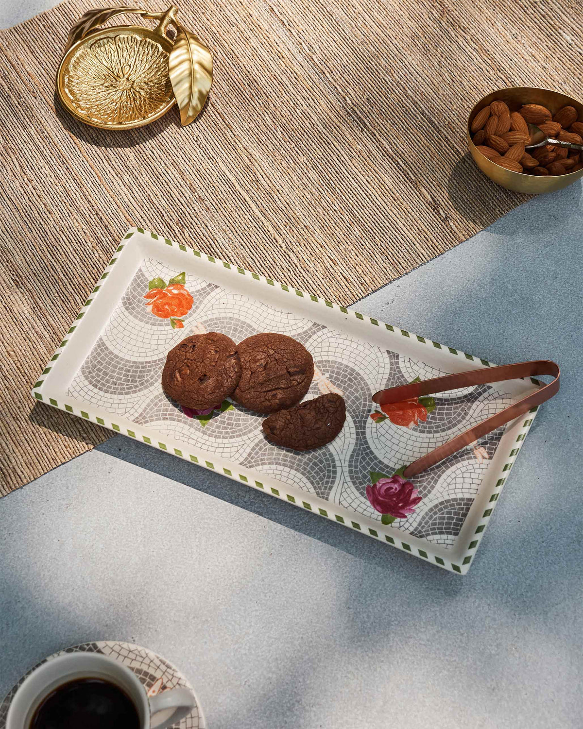 Mosaic Bloom cookie tray holding chocolate cookies with copper tongs on a table.