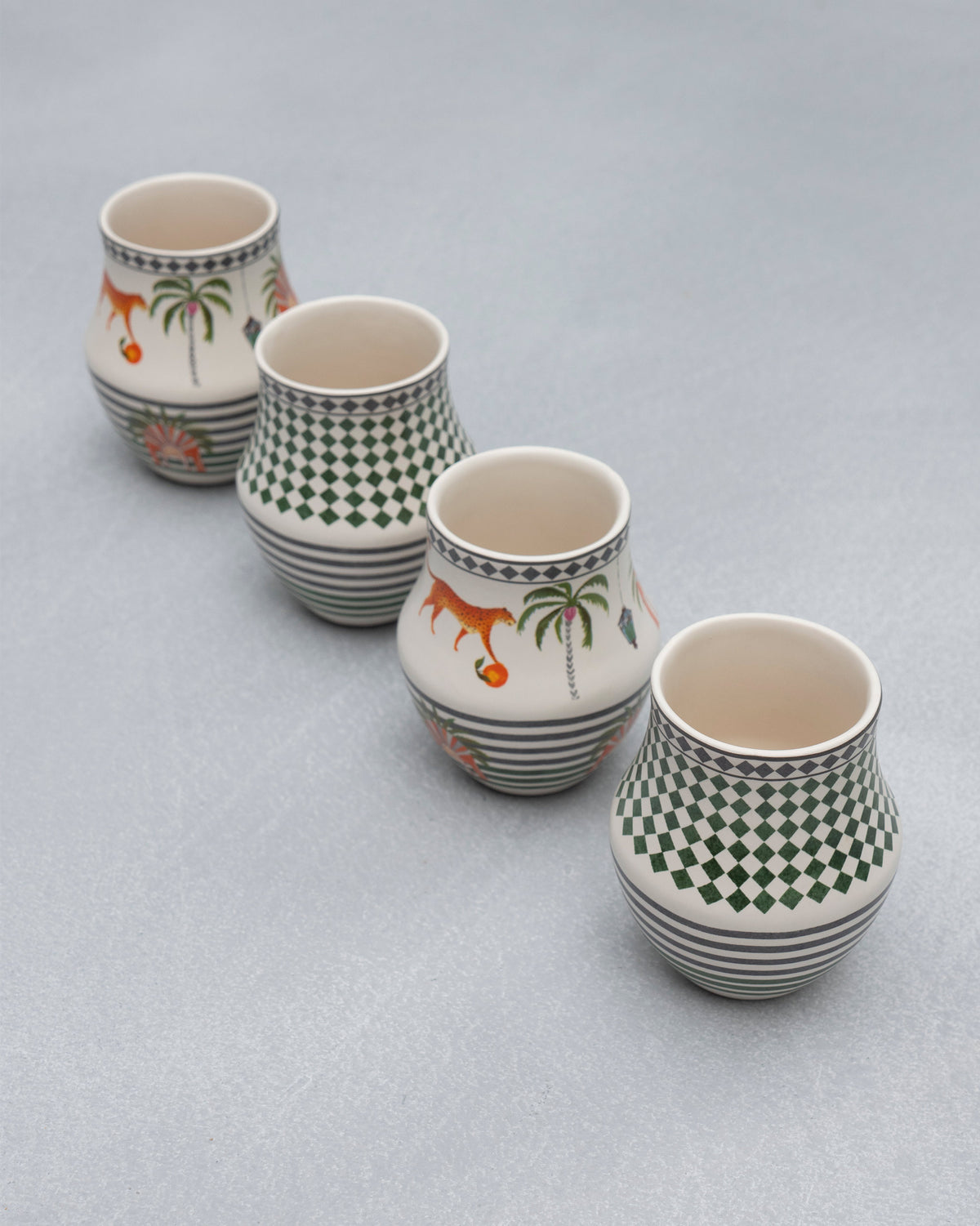 Four Dessert Palm Kulhars set in a diagonal row on a grey surface.