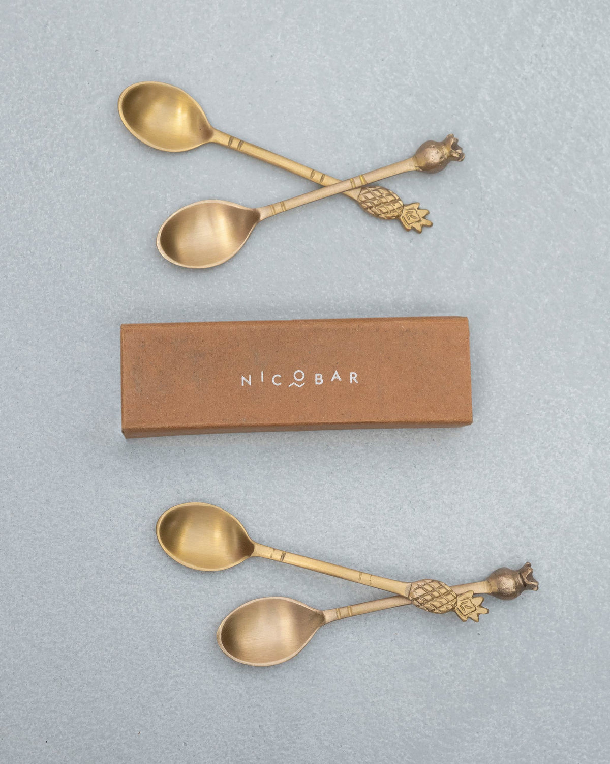Brass Dune coffee spoons arranged around a Nicobar gift box.