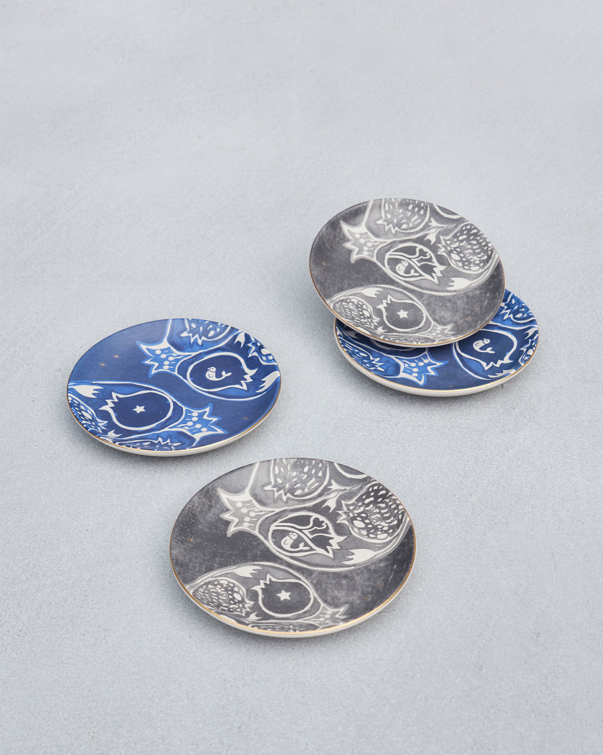 Desert Trail Tea Plates showing white pomegranates on indigo and charcoal.