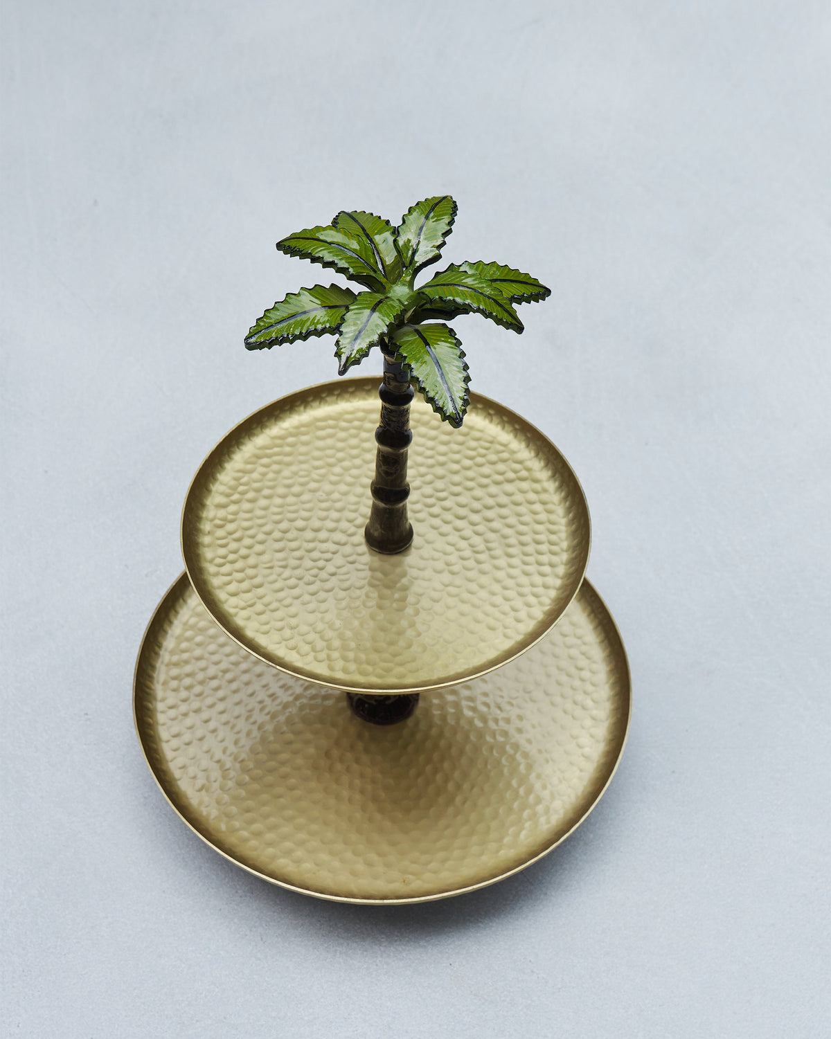 Overhead view of a two-tier Gilded Palm cake stand with hammered brass trays.