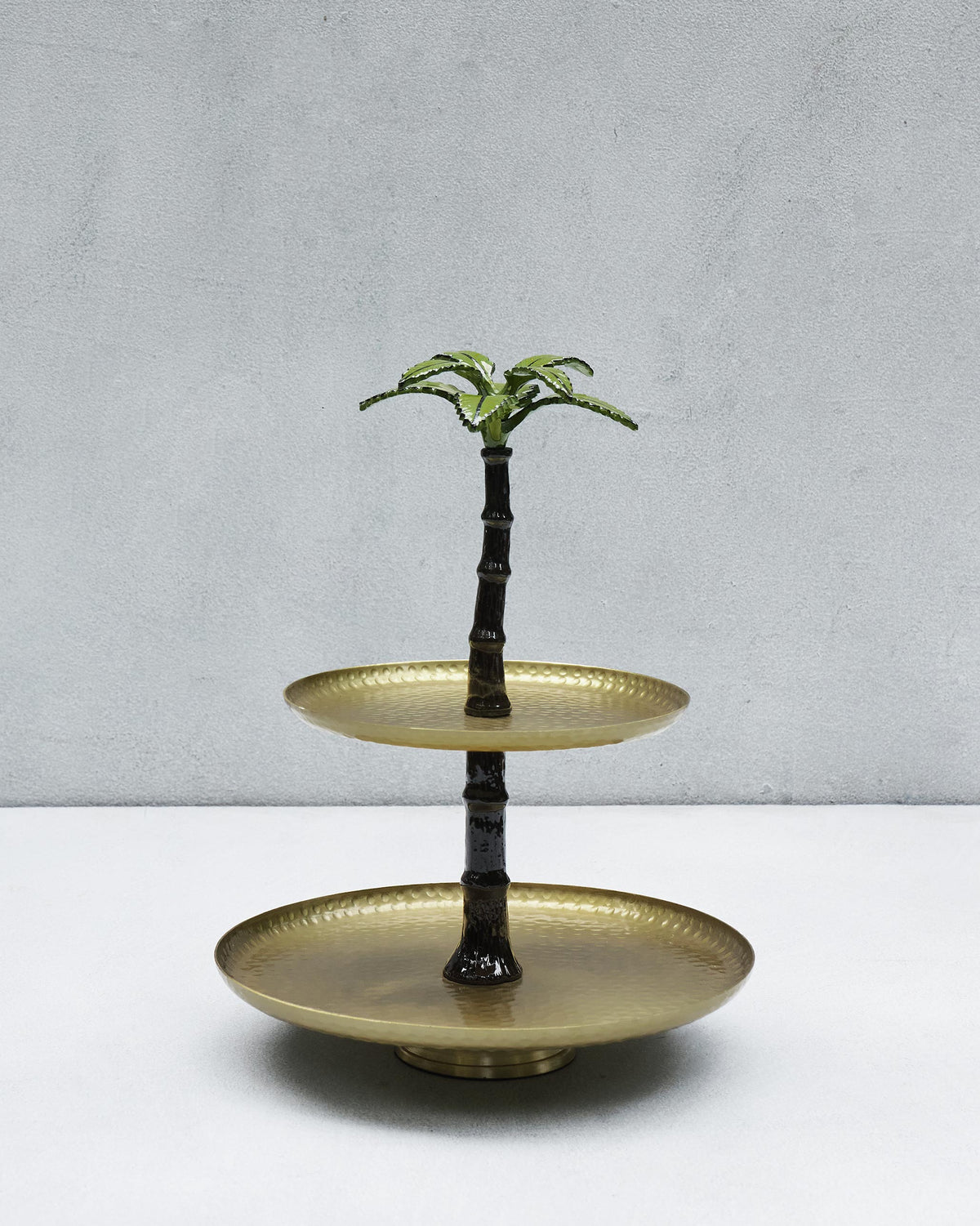 Two-tier Gilded Palm cake stand with hammered brass trays and a green palm finial.