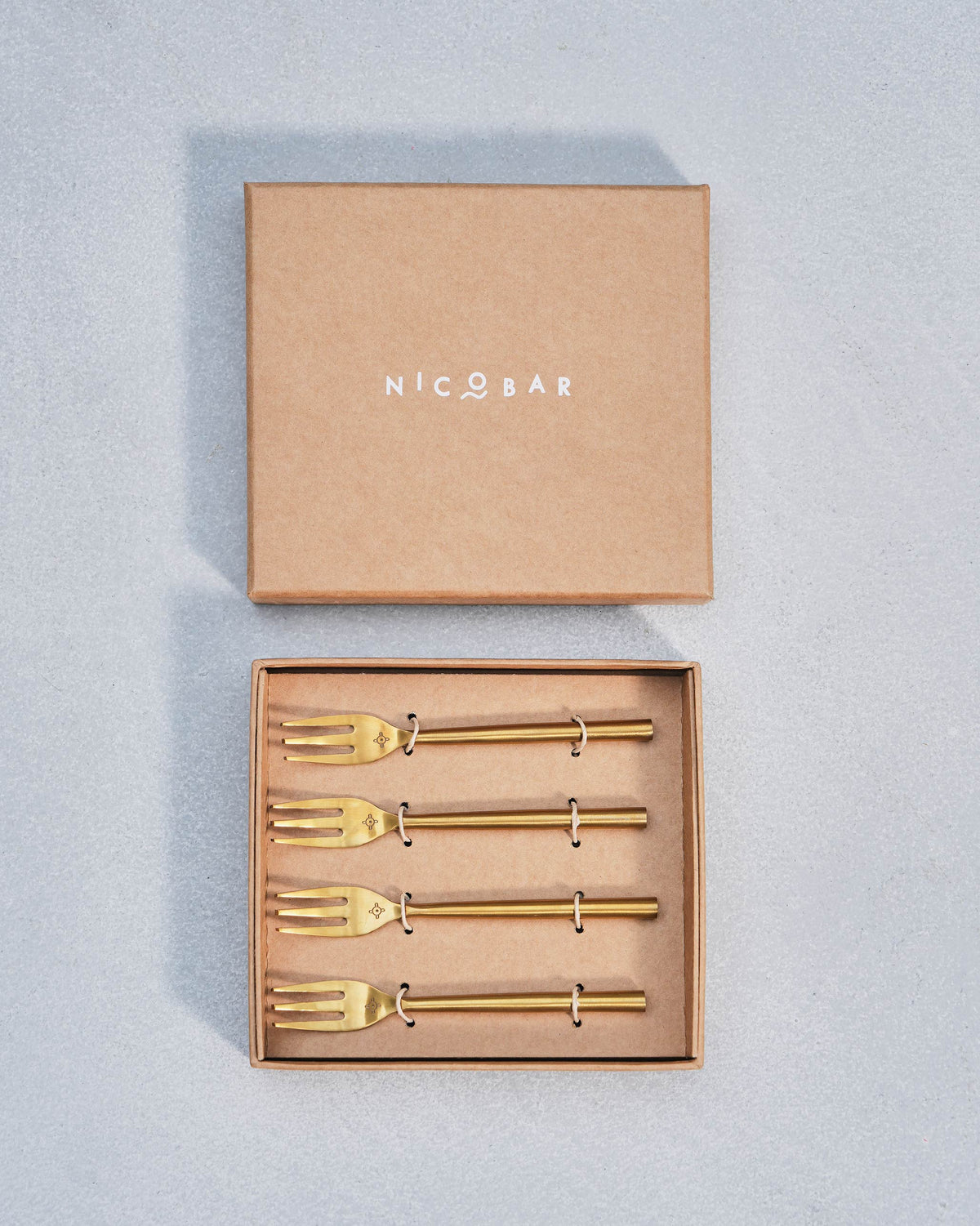 Four gold Sahara dessert forks tied in an open Nicobar gift box.