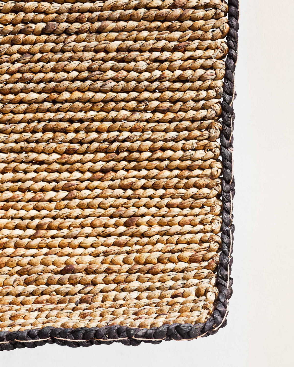 Corner of the Rabat Floor Rug showing its dark braided edge.