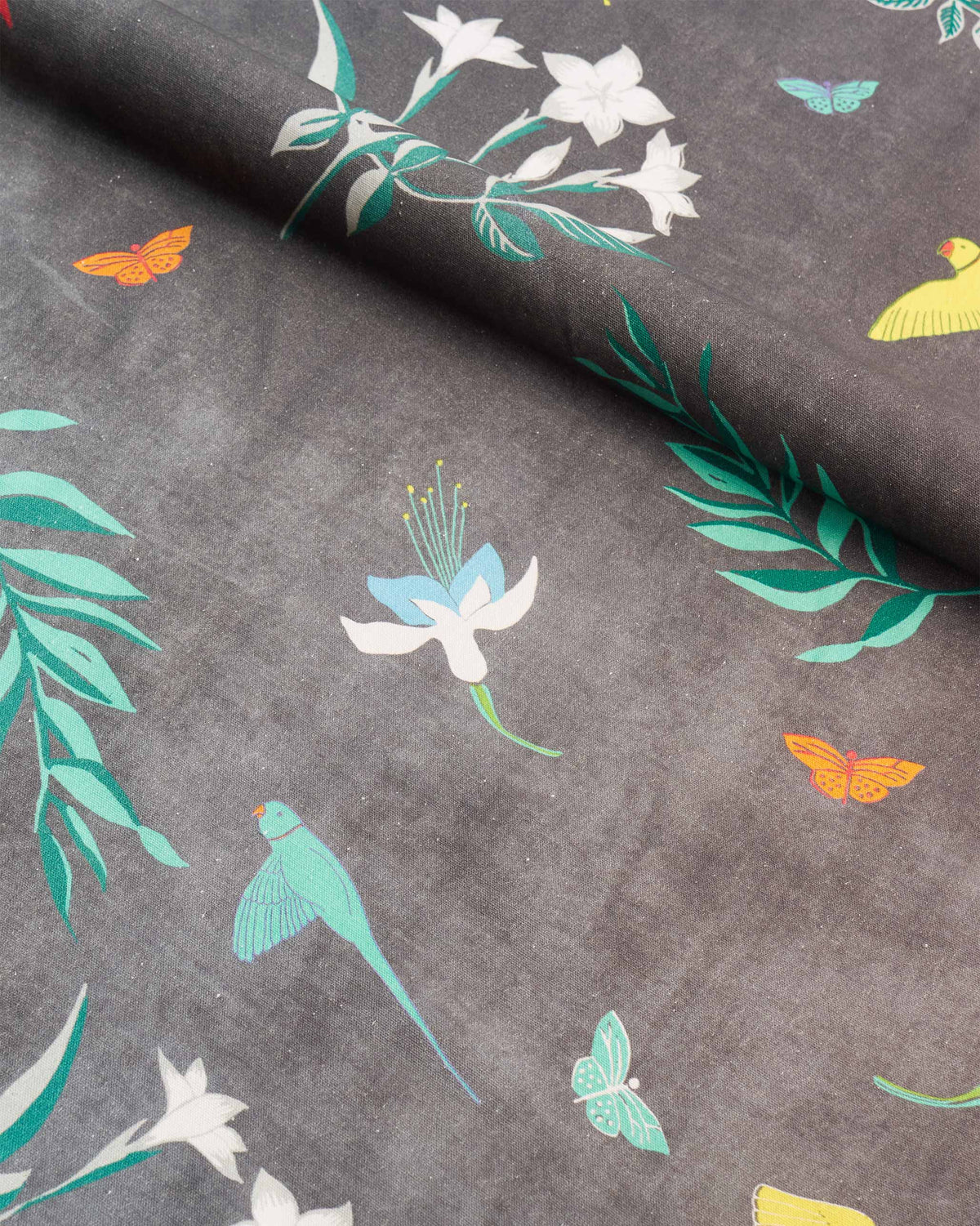 Close-up of Botanical Fabric in grey showing flowers, butterflies and parrots.