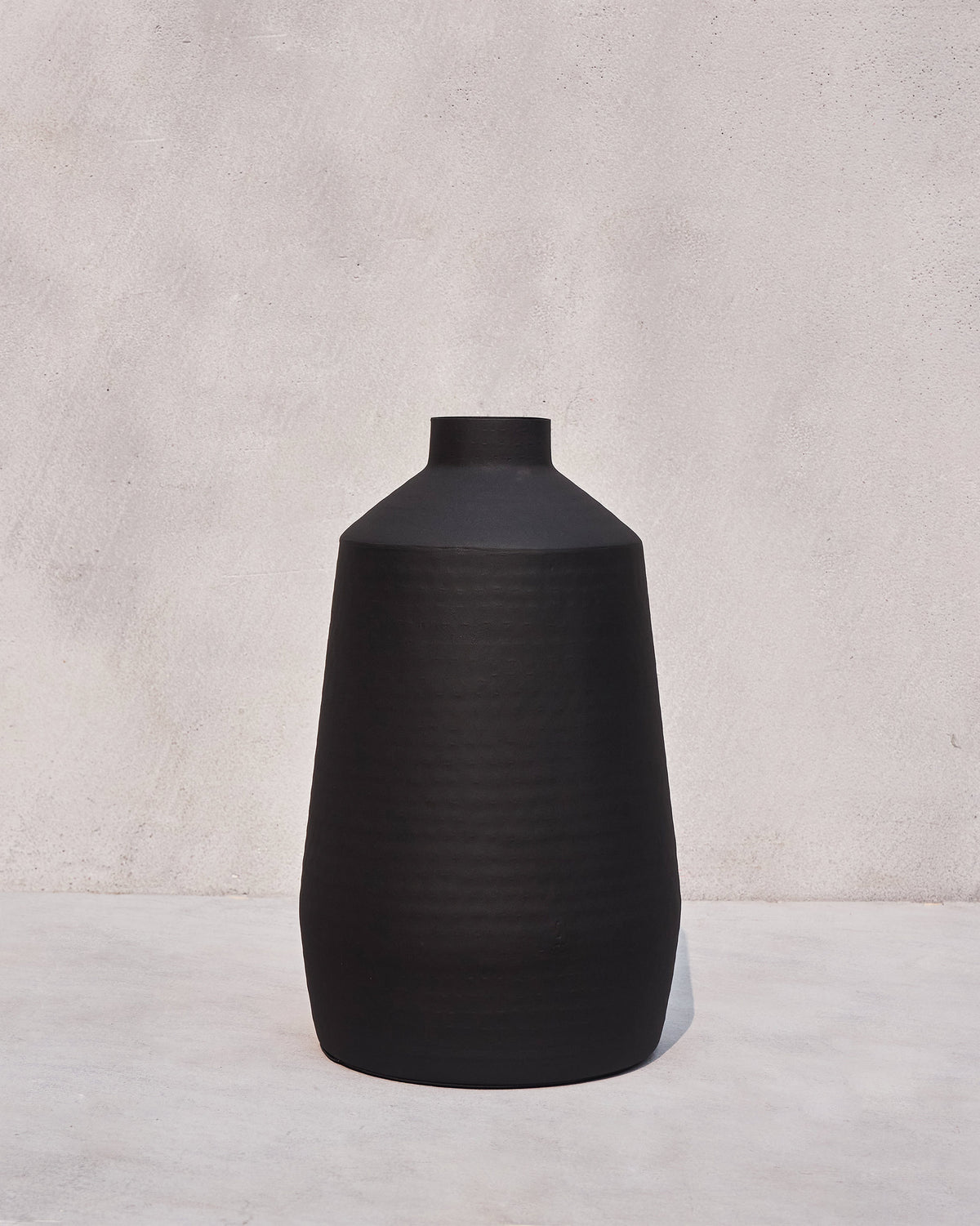 Tall matte black Dhara vase with a rounded body and short neck.