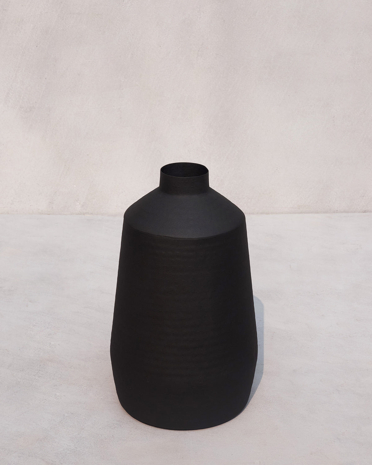Three-quarter view of a tall matte black Dhara vase.