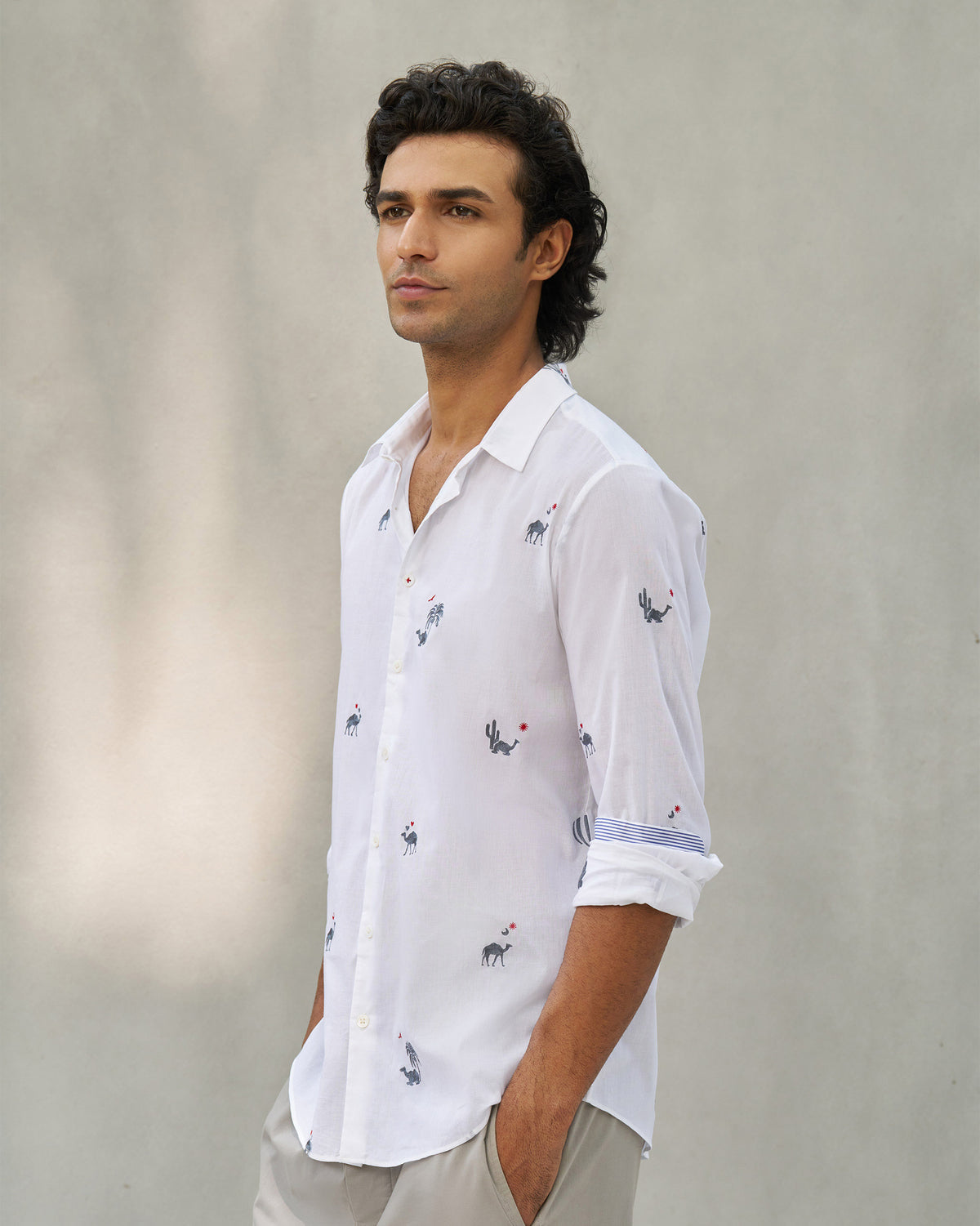 Person wearing a white Hakuna shirt with camel motifs and striped cuff lining.