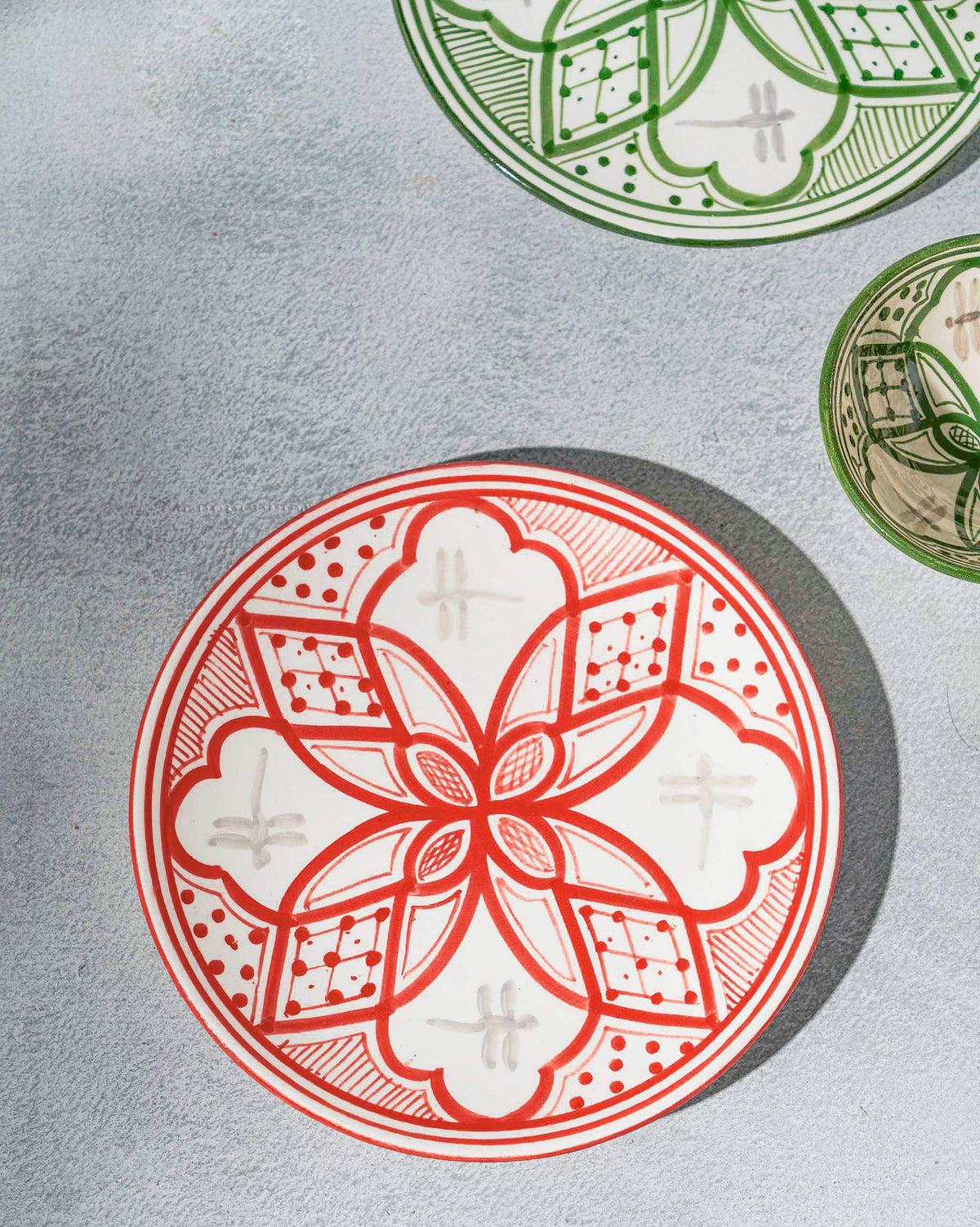 Red Mosaic Oasis quarter plate styled beside green patterned plates.
