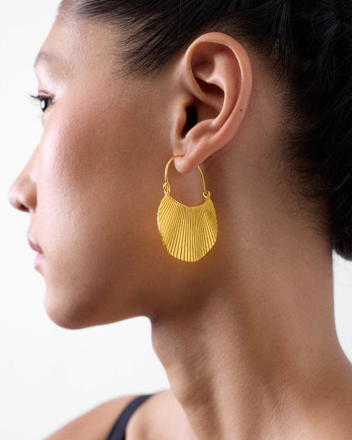 Side profile of a gold Pankha fan bali on a person.