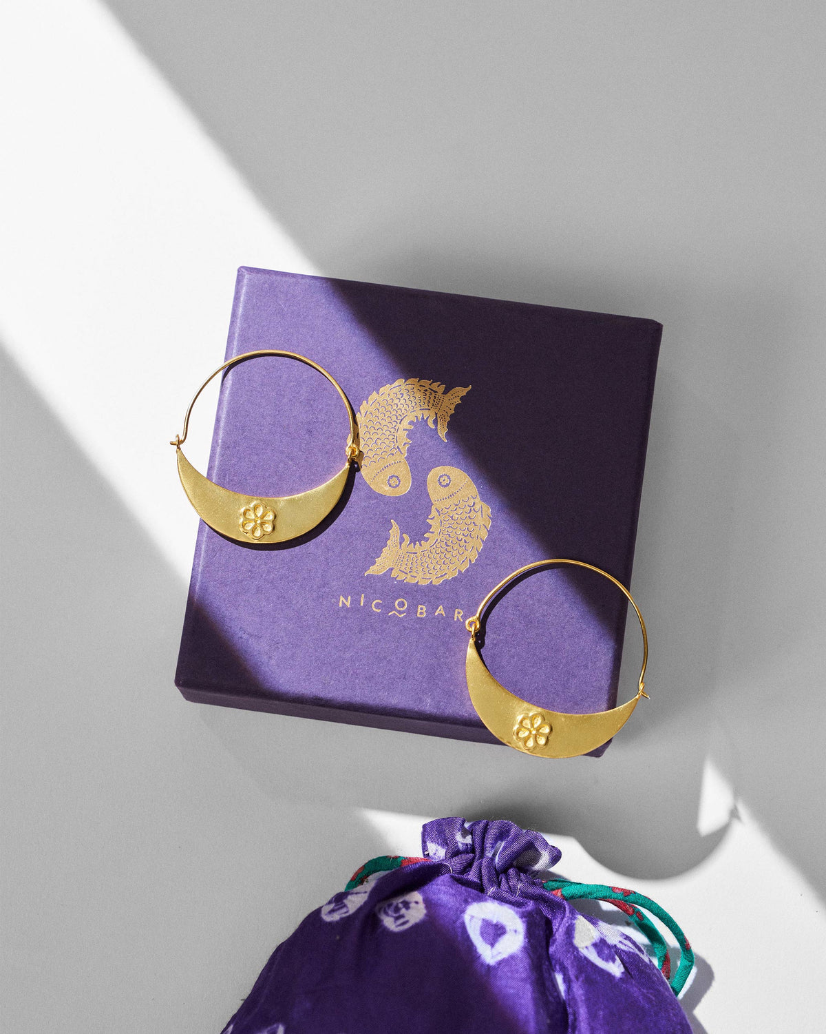 Gold Boat balis with floral plates on a purple Nicobar gift box.