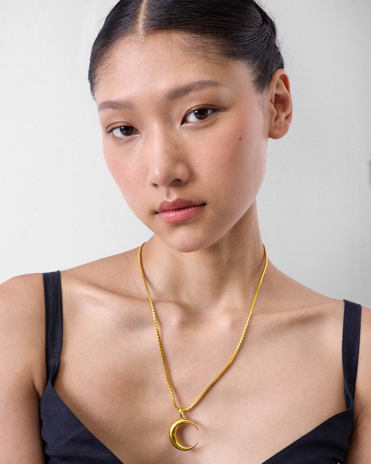 Person wearing a gold crescent Moonfall necklace.