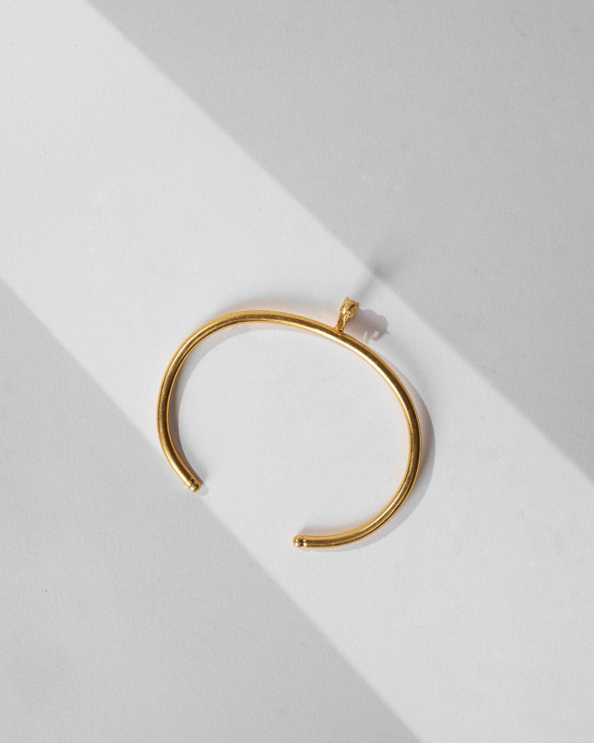 Antique gold haathi cuff with elephant charm laid flat.