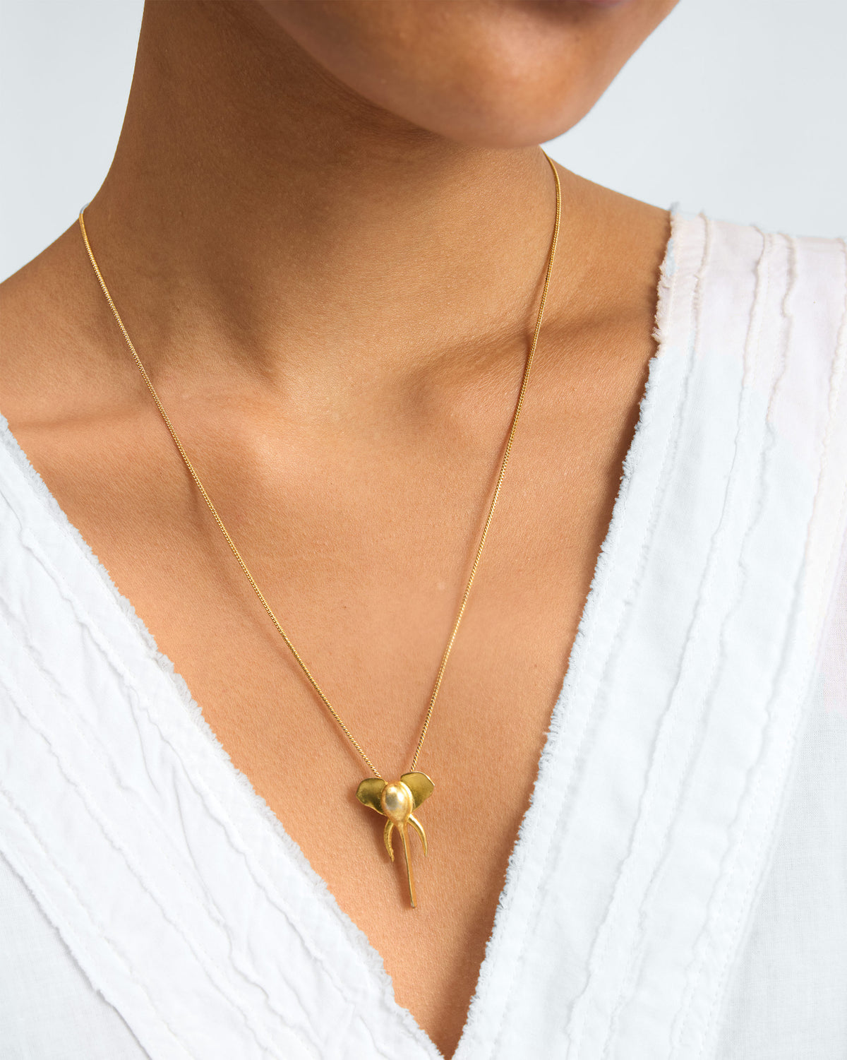 Person wearing an Elephant charm pendant on a fine gold chain.