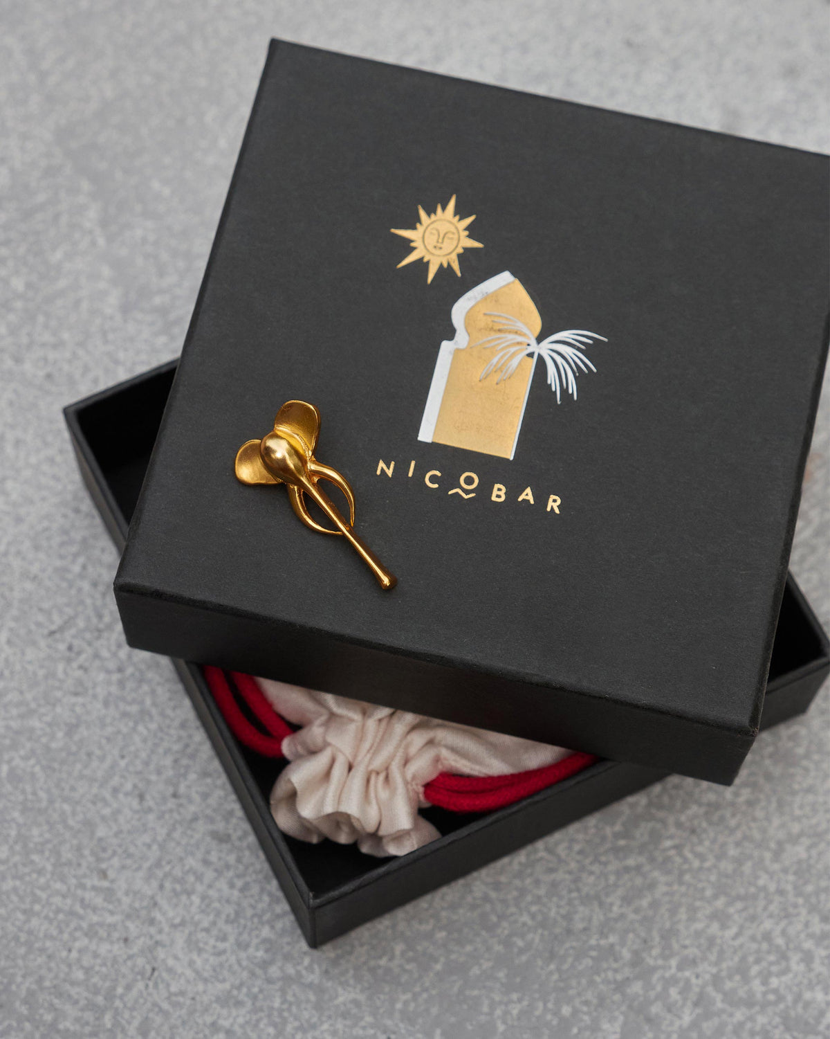 Elephant charm resting on a black gift box beside a pale pouch.