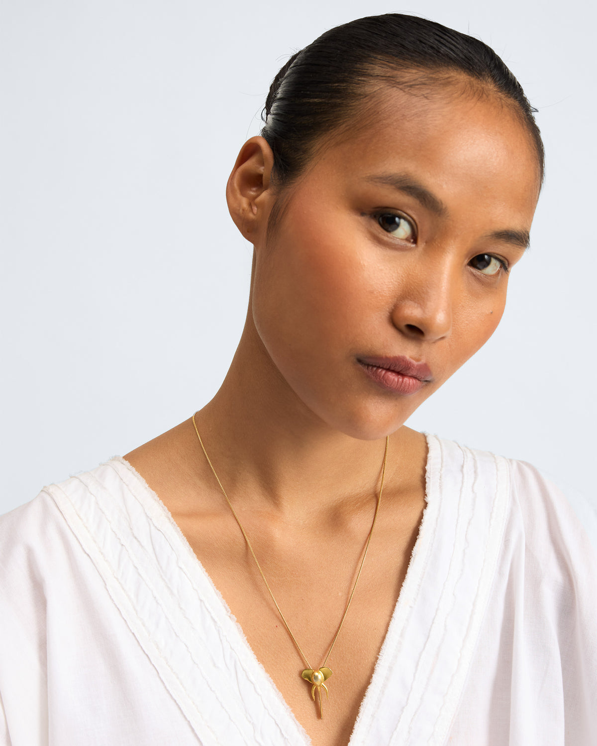 Person wearing an Elephant charm necklace, pendant centred at the chest.