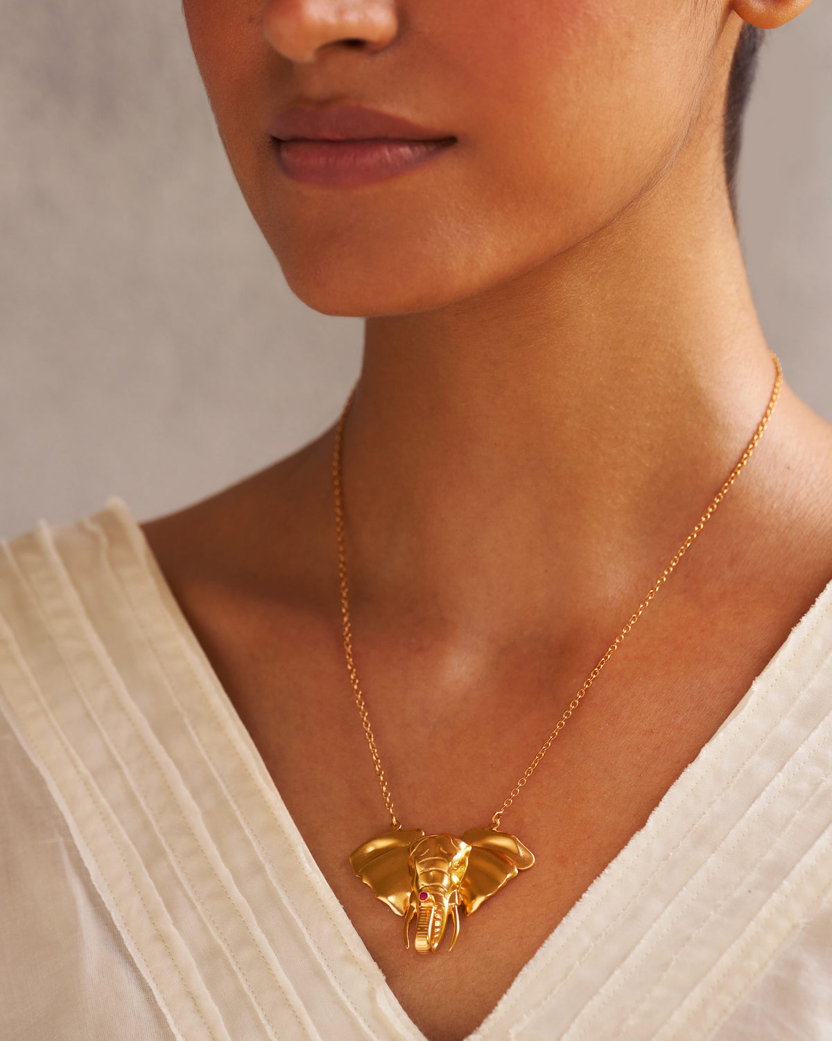 Person wearing a Haathi Necklace with an elephant-head pendant on a fine gold chain.