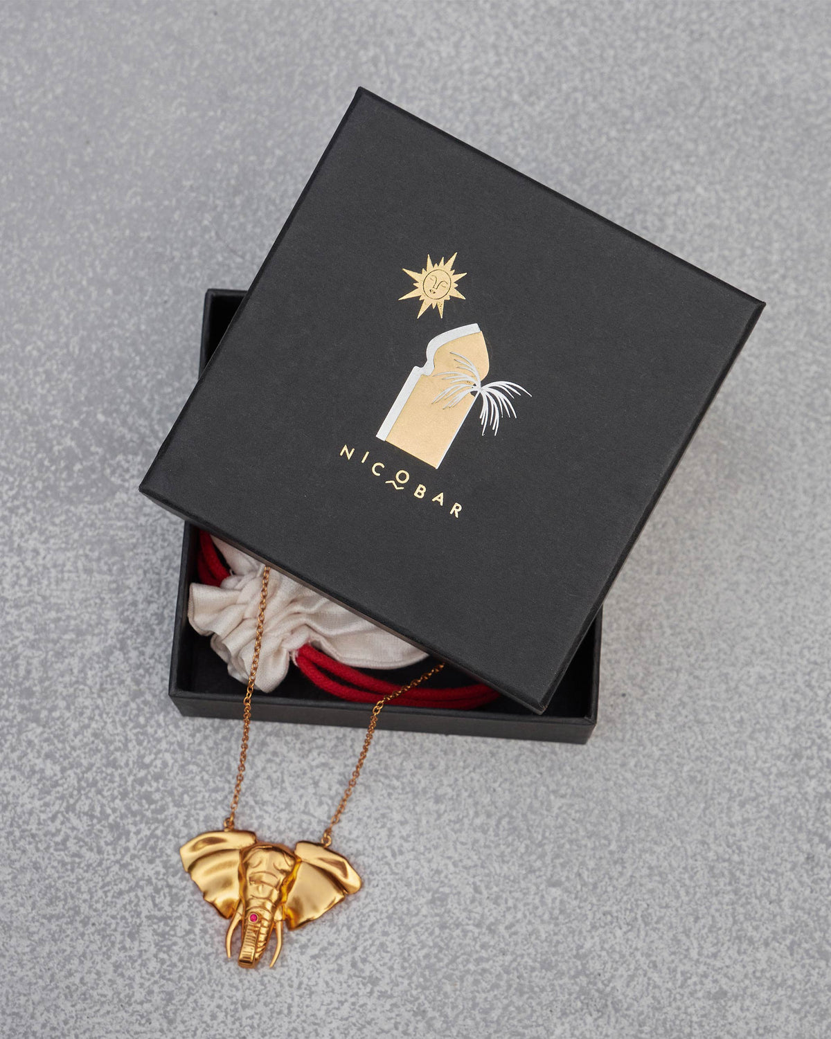 Haathi Necklace hanging out of a black Nicobar gift box.
