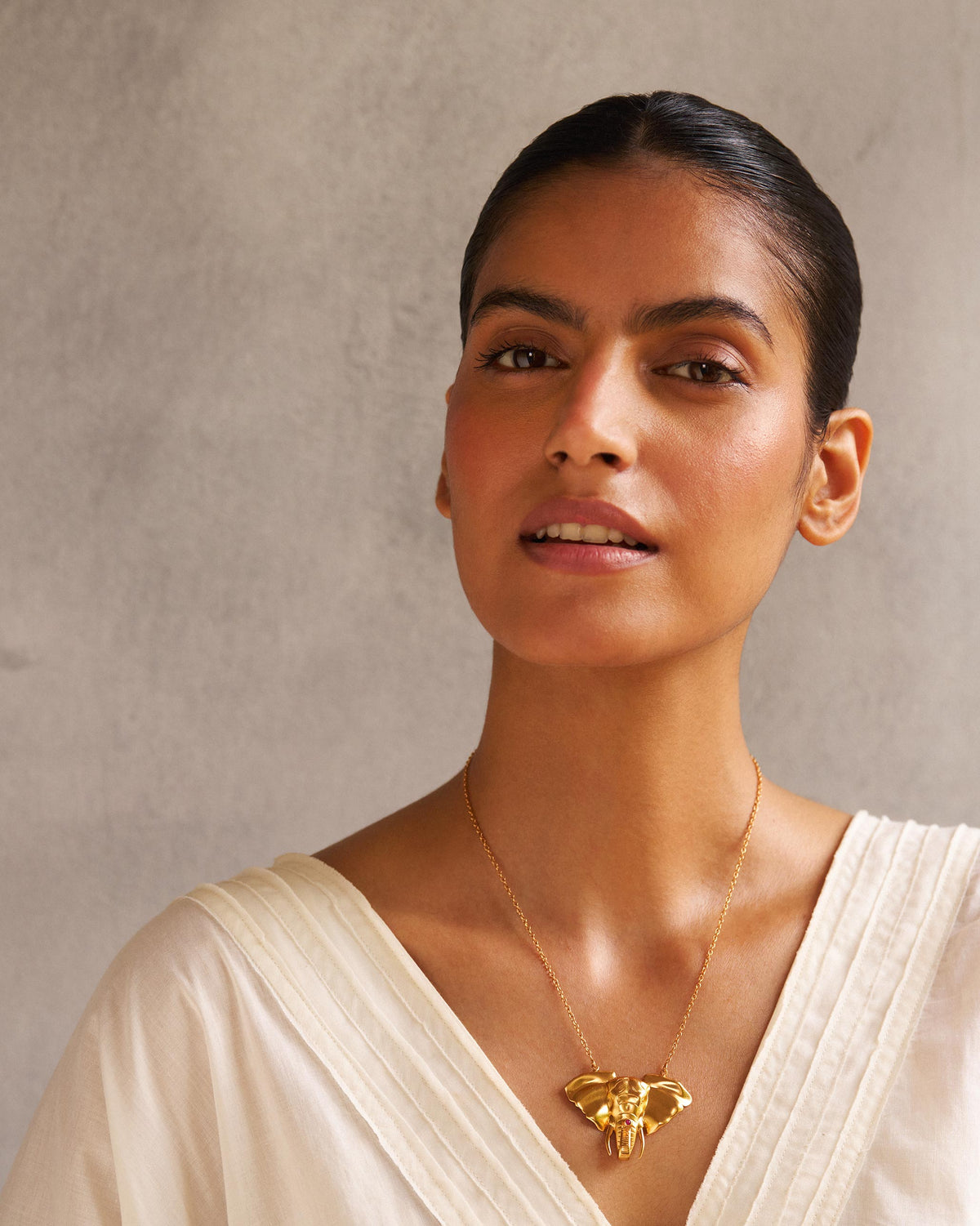 Person wearing a Haathi Necklace, pendant at the neckline.