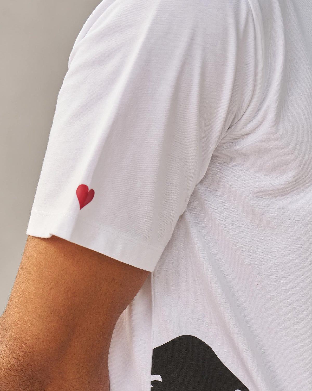 Close-up of a white Peekaboo Dalmation T-shirt sleeve with a red heart.