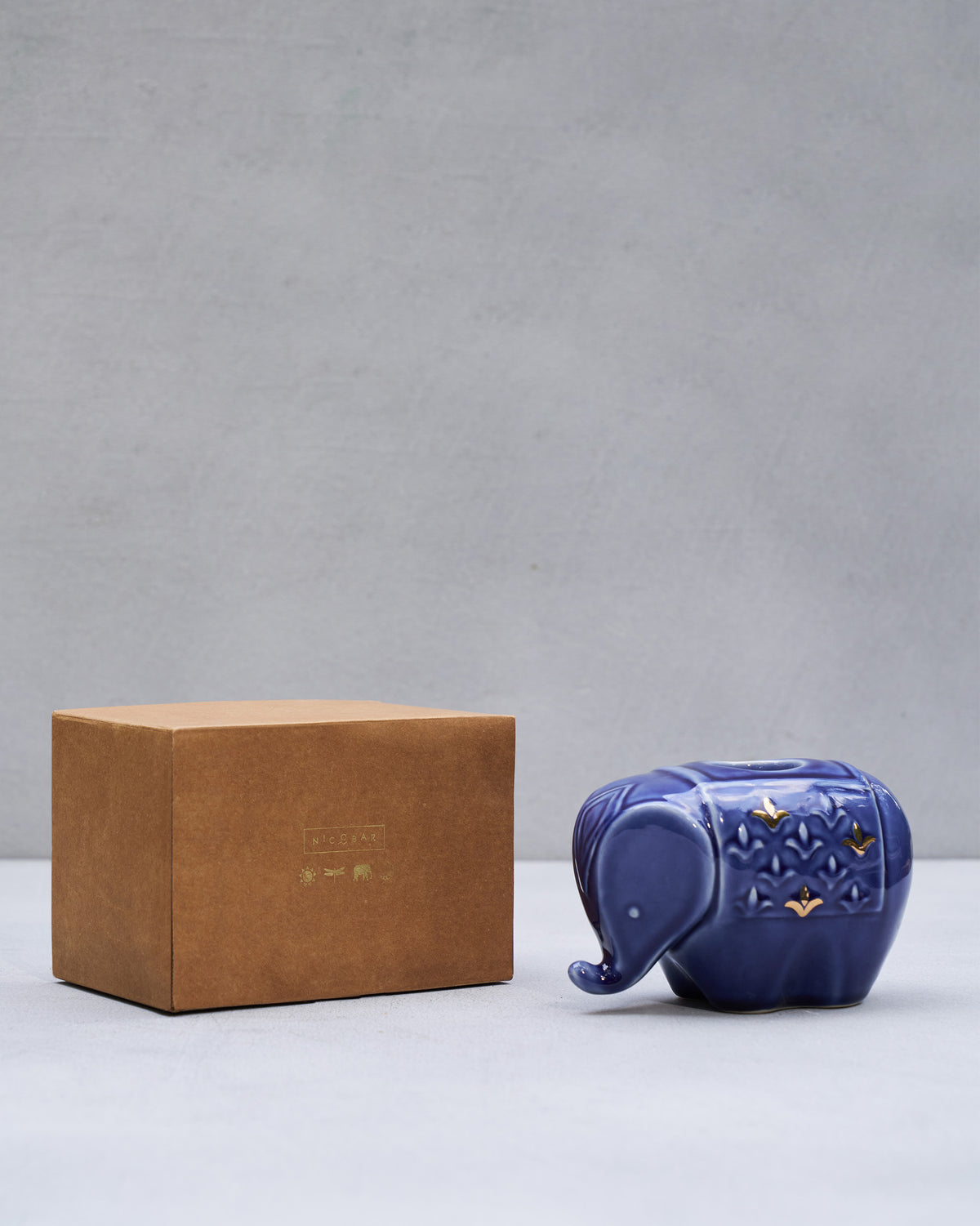 Blue Tusker votive displayed beside a kraft Nicobar gift box.