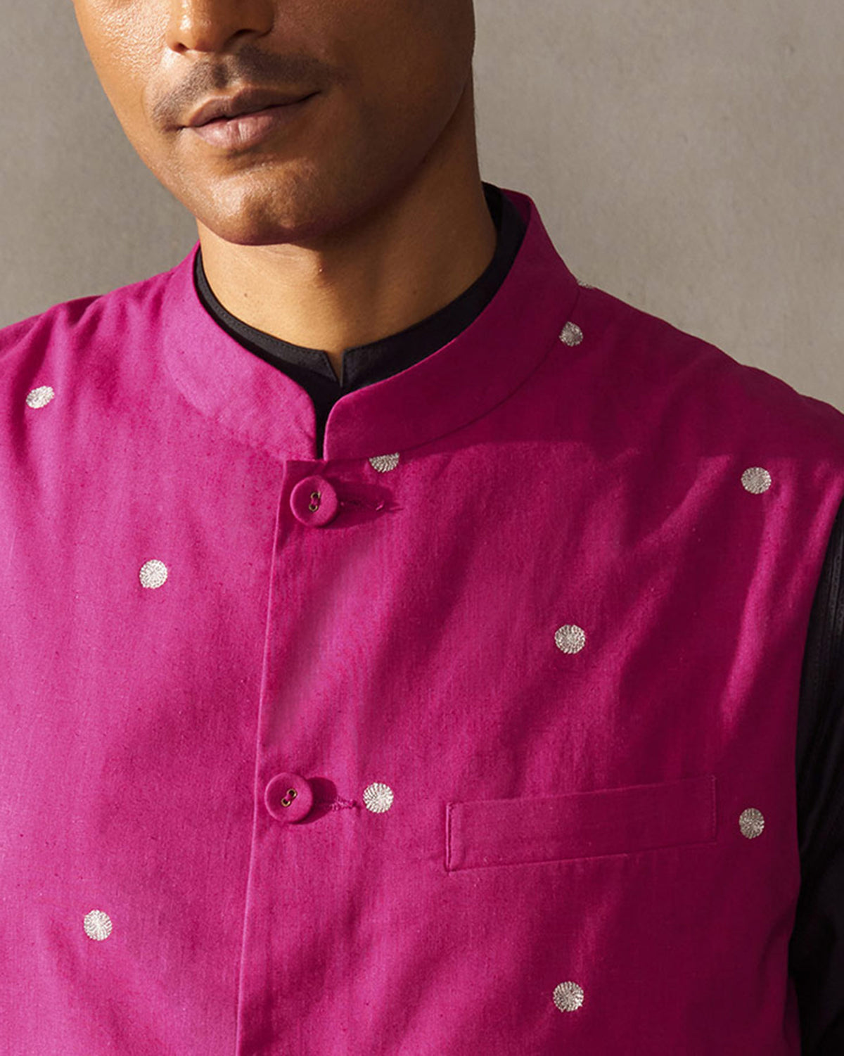 Close-up of a magenta Nehru jacket showing silver embroidered motifs.