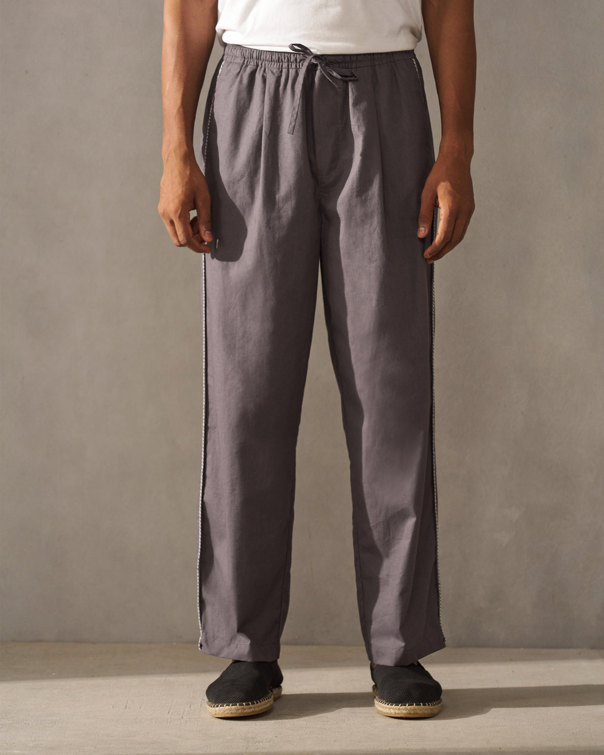 Person wearing charcoal Tom Trousers with a drawstring waist.