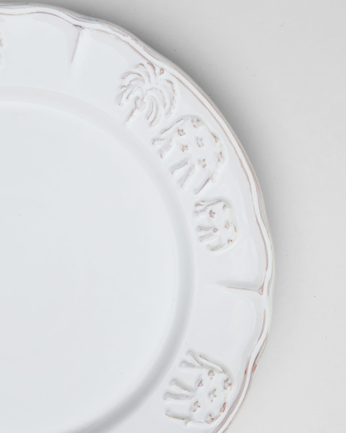 Close-up of Ele Palm Dinner Plate showing embossed palm and elephant motifs on the rim.