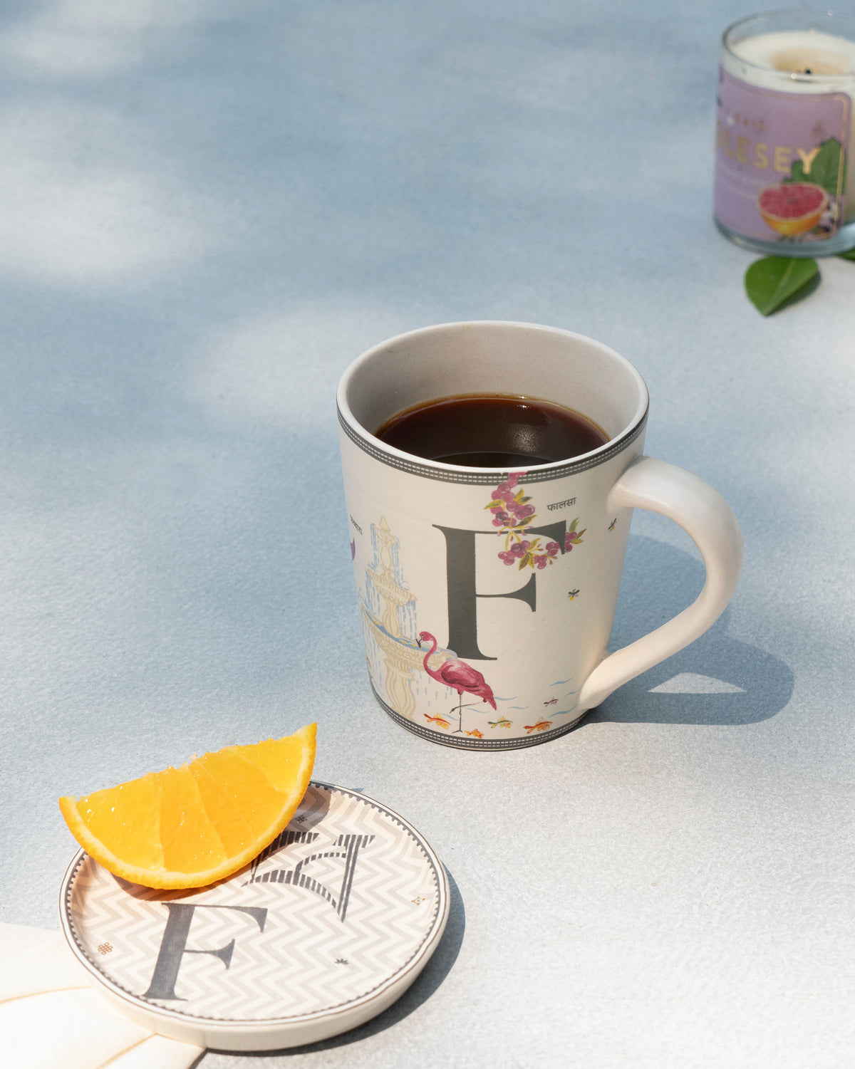 F Alphabet mug filled with coffee beside a matching letter F coaster.