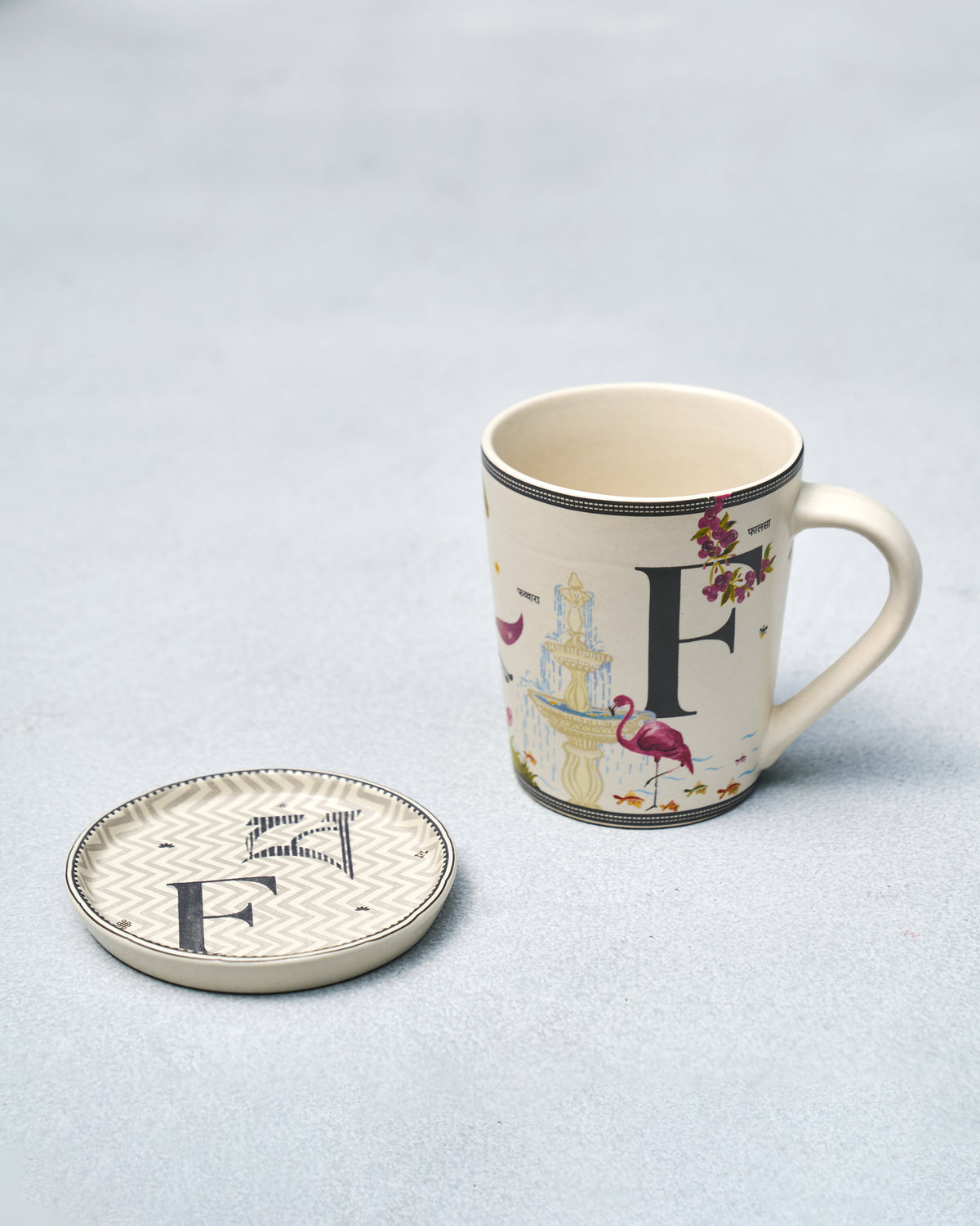 F Alphabet mug with flamingo and fountain beside a matching letter F coaster.