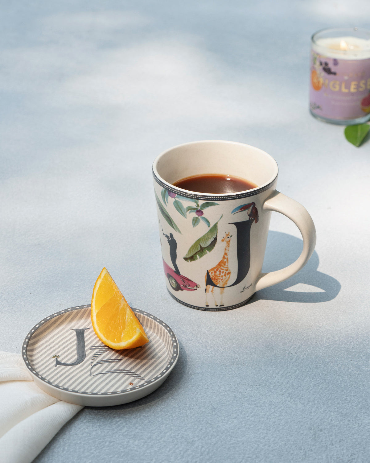 J Alphabet mug filled with coffee beside a matching letter J coaster.