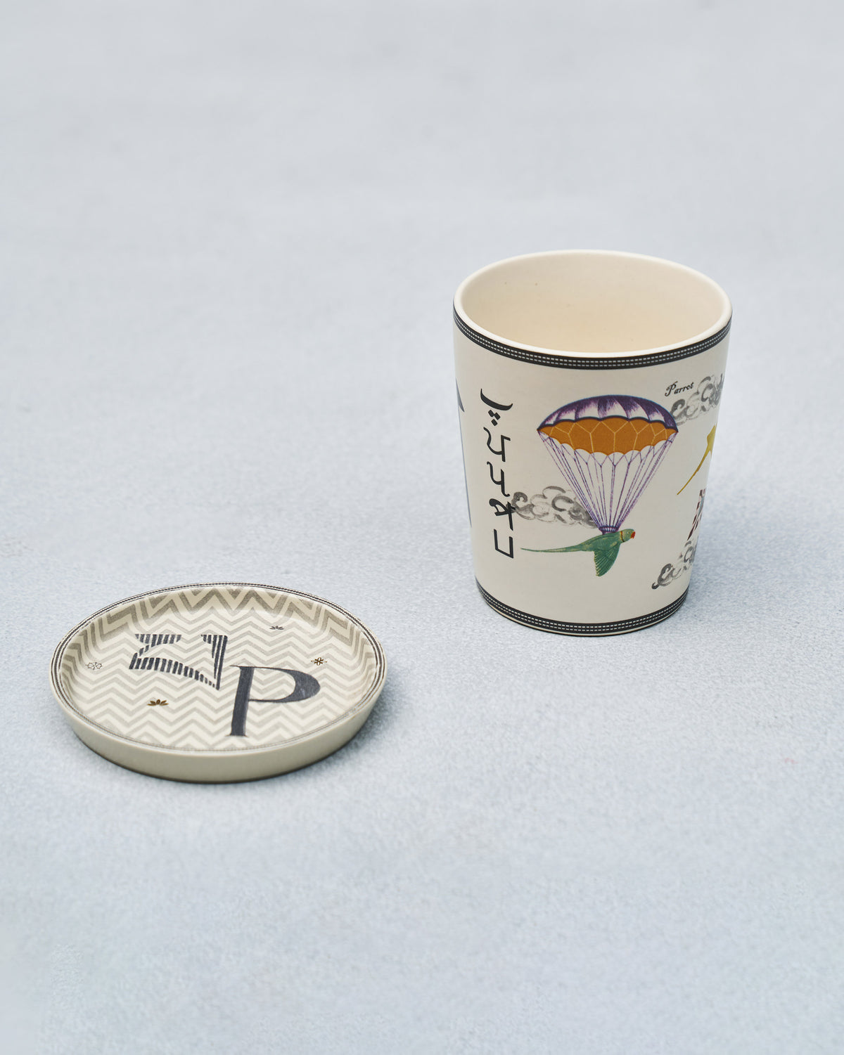 P alphabet cup with a parrot and parachute motif beside a P coaster.