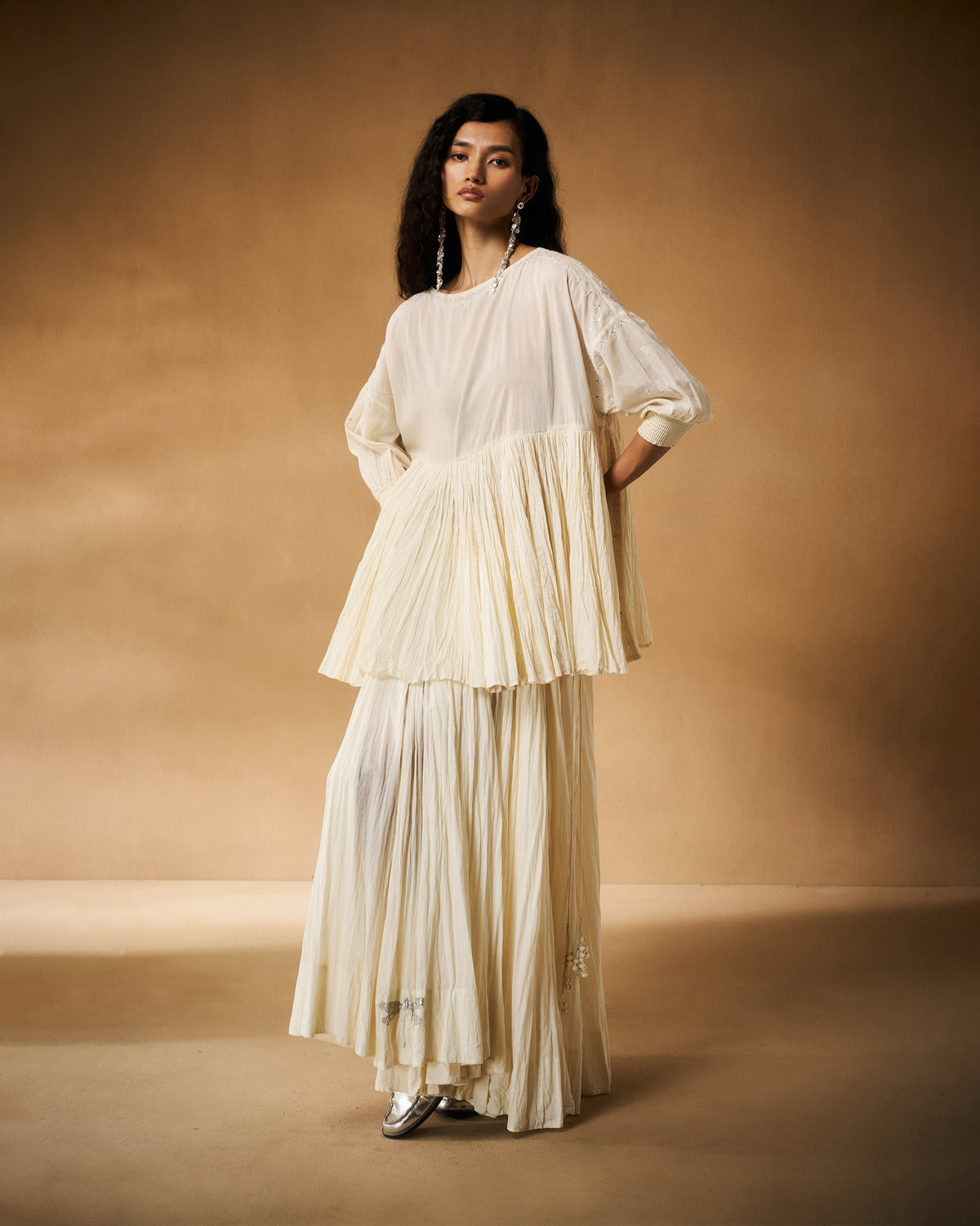 Person wearing an ivory chikankari Taabir top with matching pleated trousers.