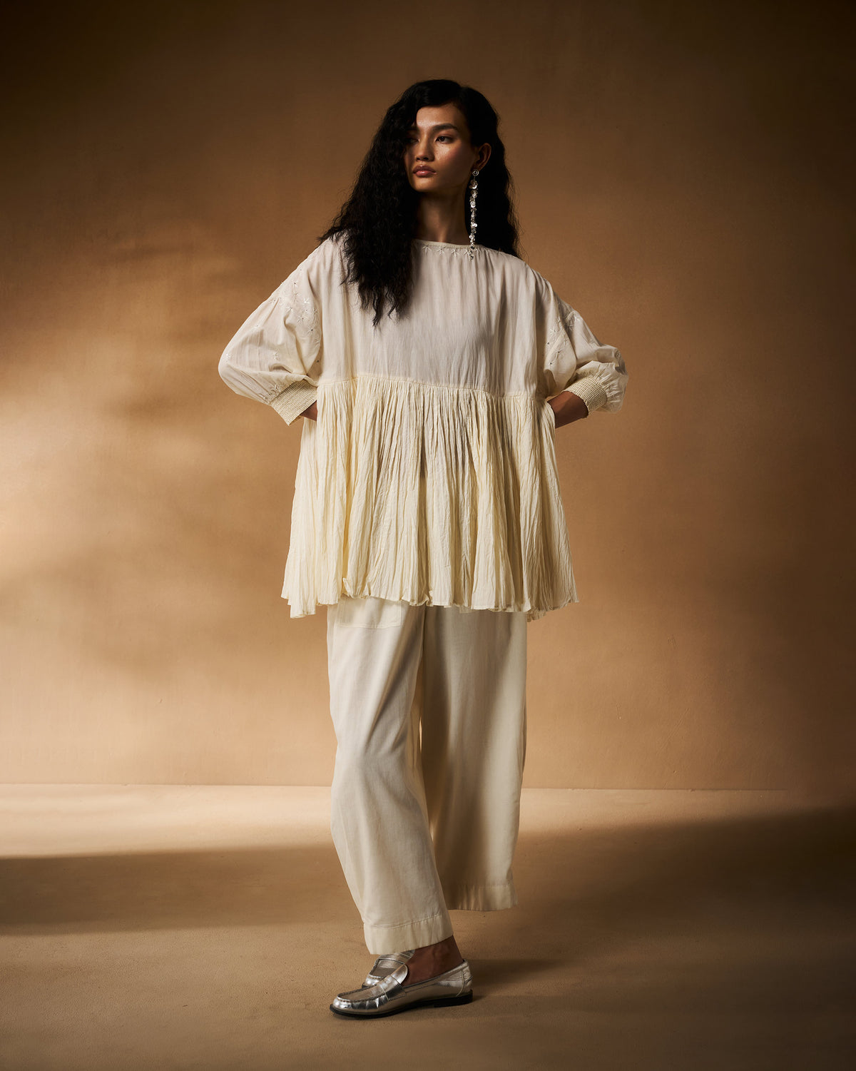 Person wearing an ivory chikankari Taabir top with a flared pleated peplum.