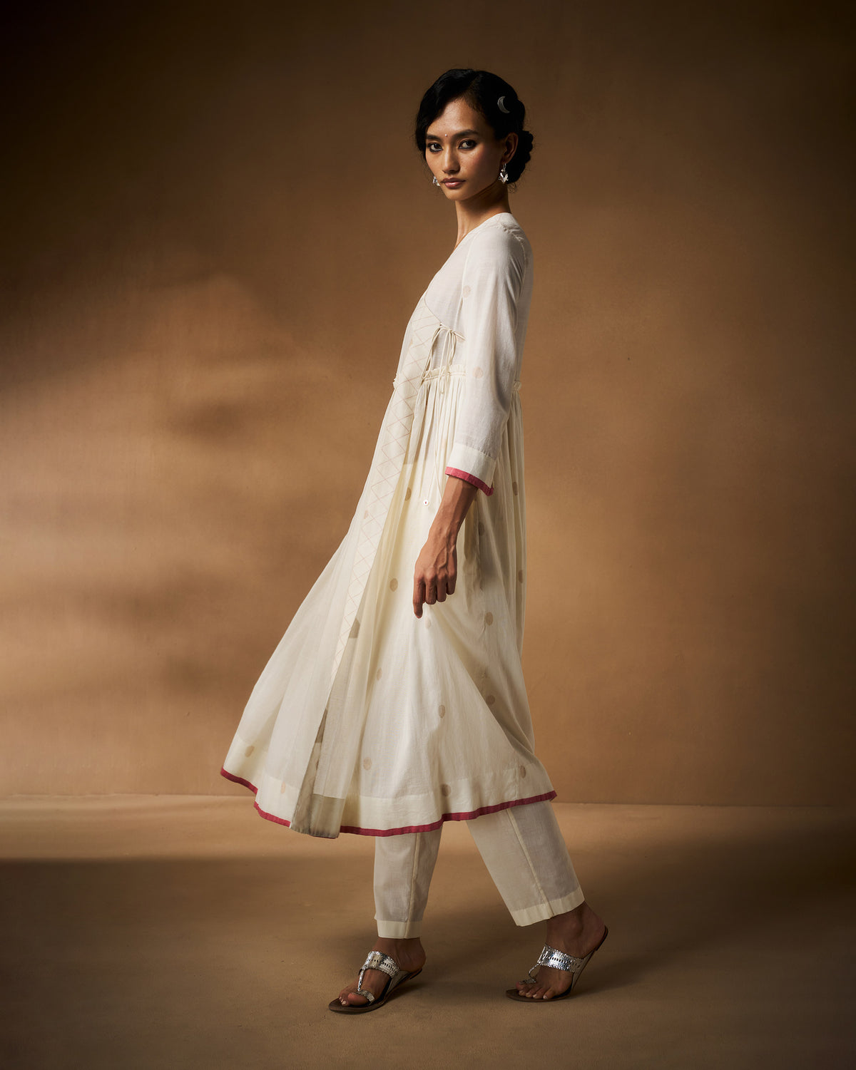 Person wearing a flared ivory Sukoon angrakha with pink hem trim.
