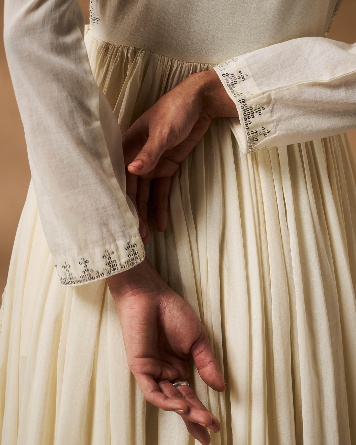 Close-up of ivory Aafreen Angrakha pleats and a silver embroidered cuff.