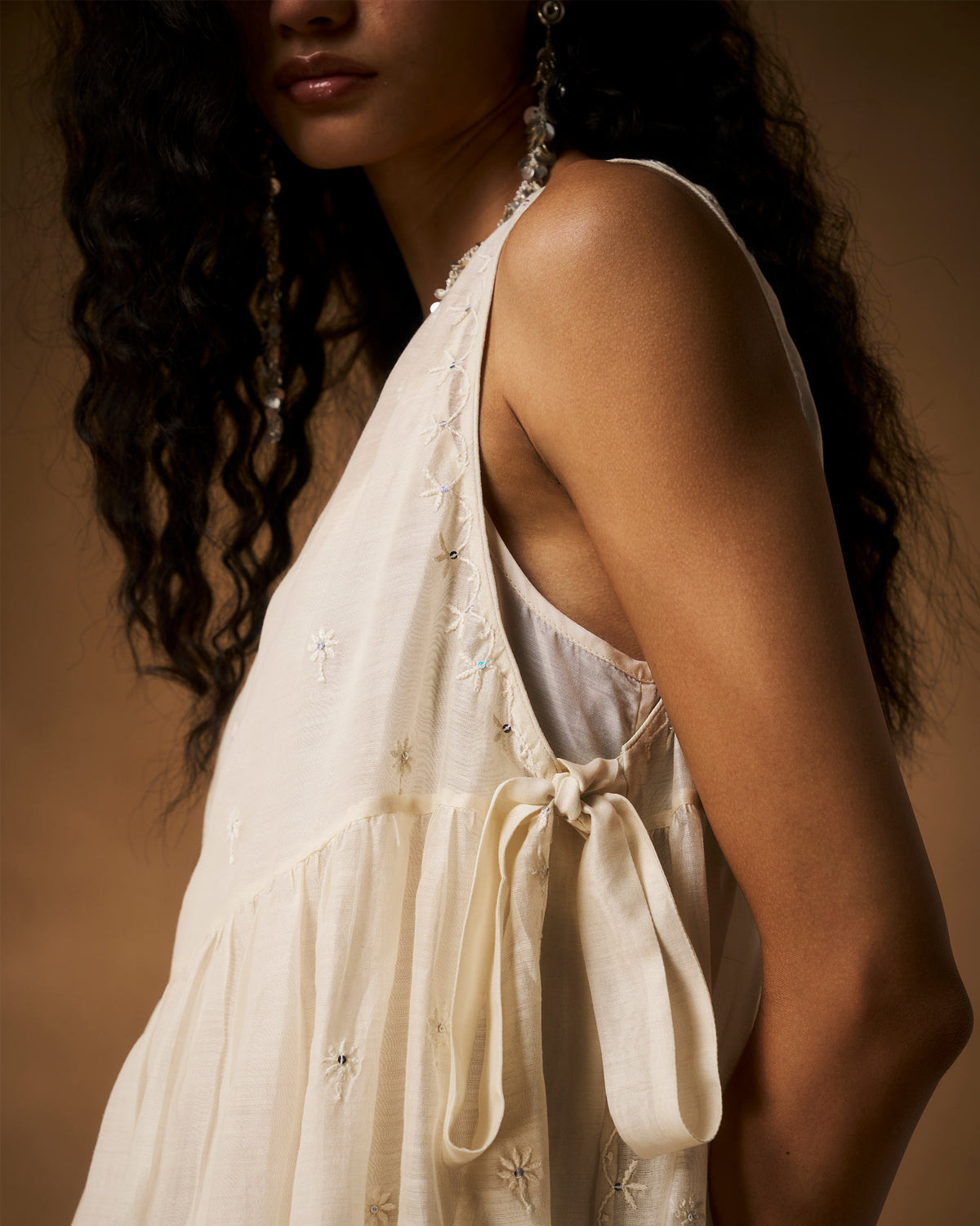 Close-up of the ivory Afra tunic side-tie bow with daisy chikankari motifs.