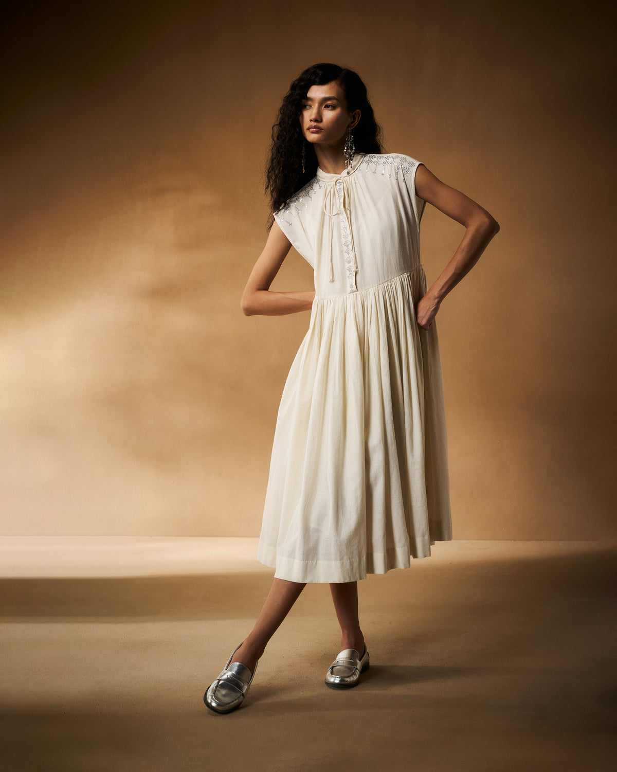 Person wearing an ivory Mina Dress with a gathered midi skirt.