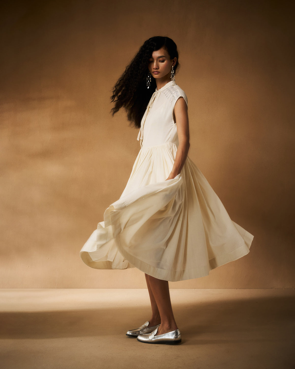 Person wearing an ivory Mina Dress with the skirt flaring in motion.