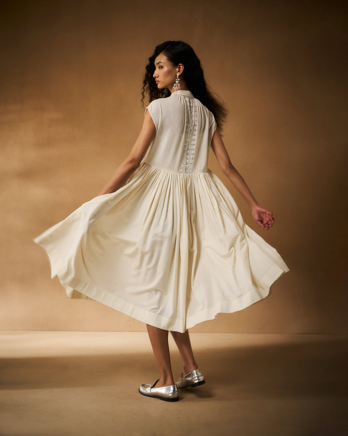 Back of an ivory Mina Dress with a full skirt twirling out.